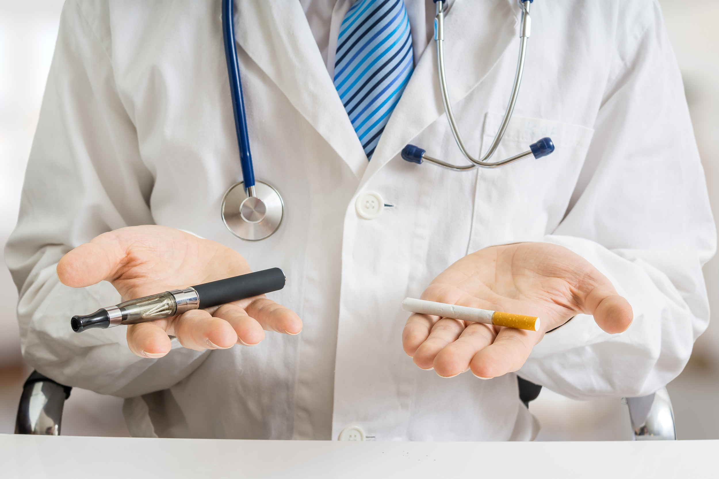 Doctor holding a cigarette and a vaporizer