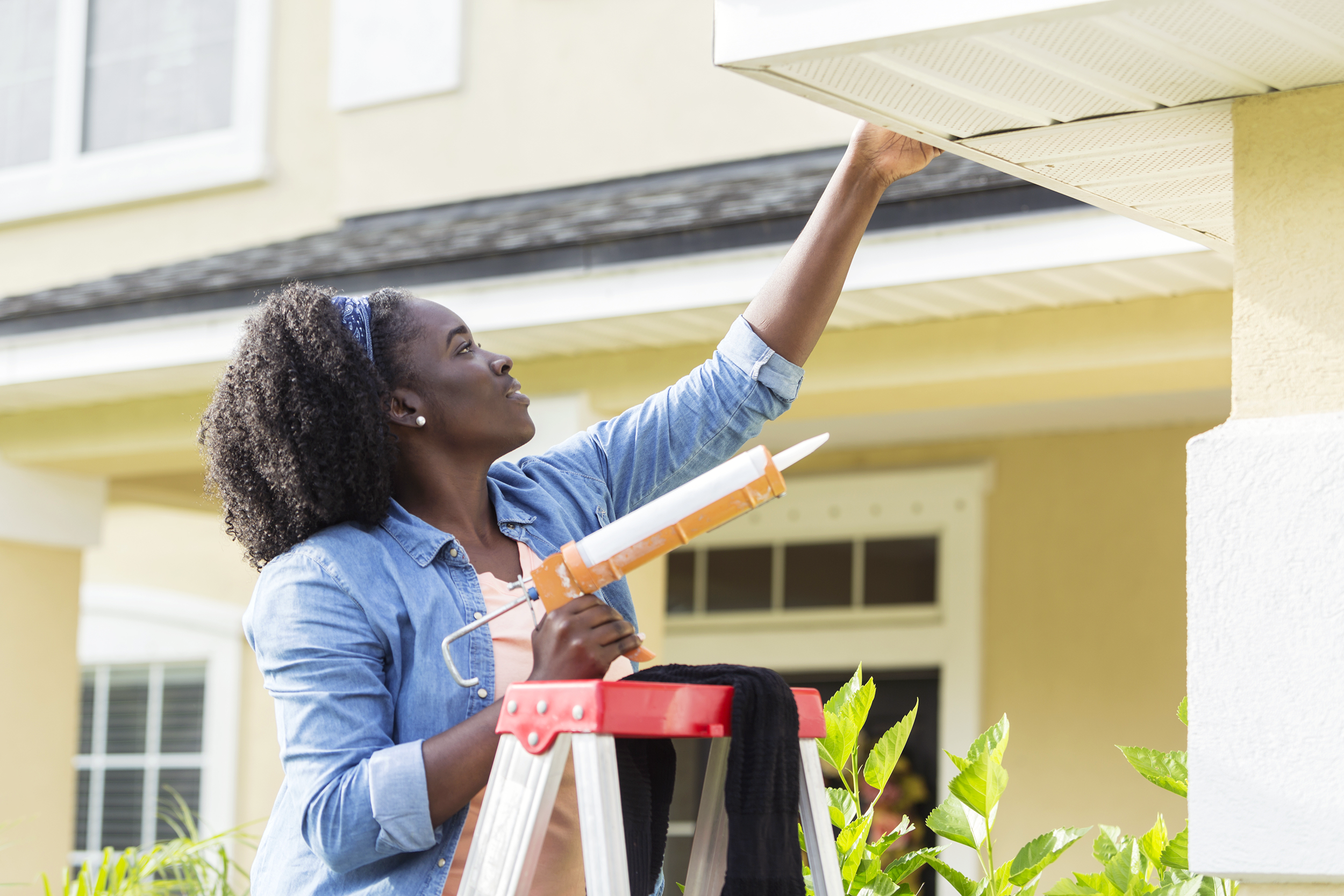 Woman on a ladder repairing home