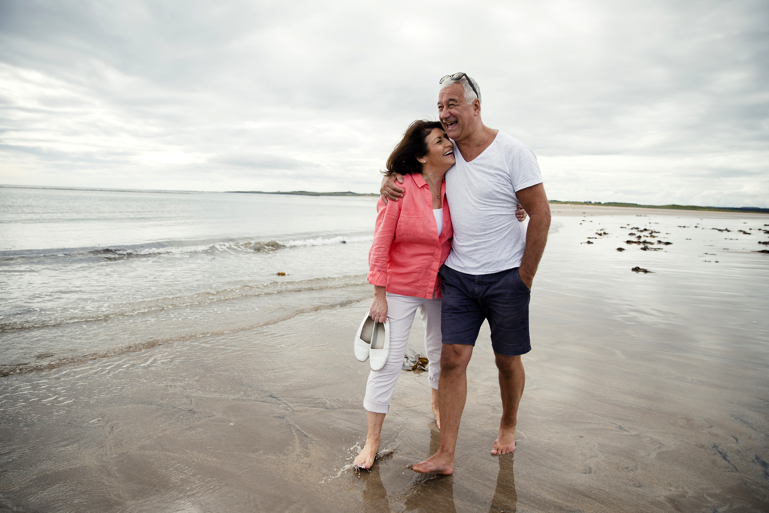 Older couple walking on the beach on a cloudy day