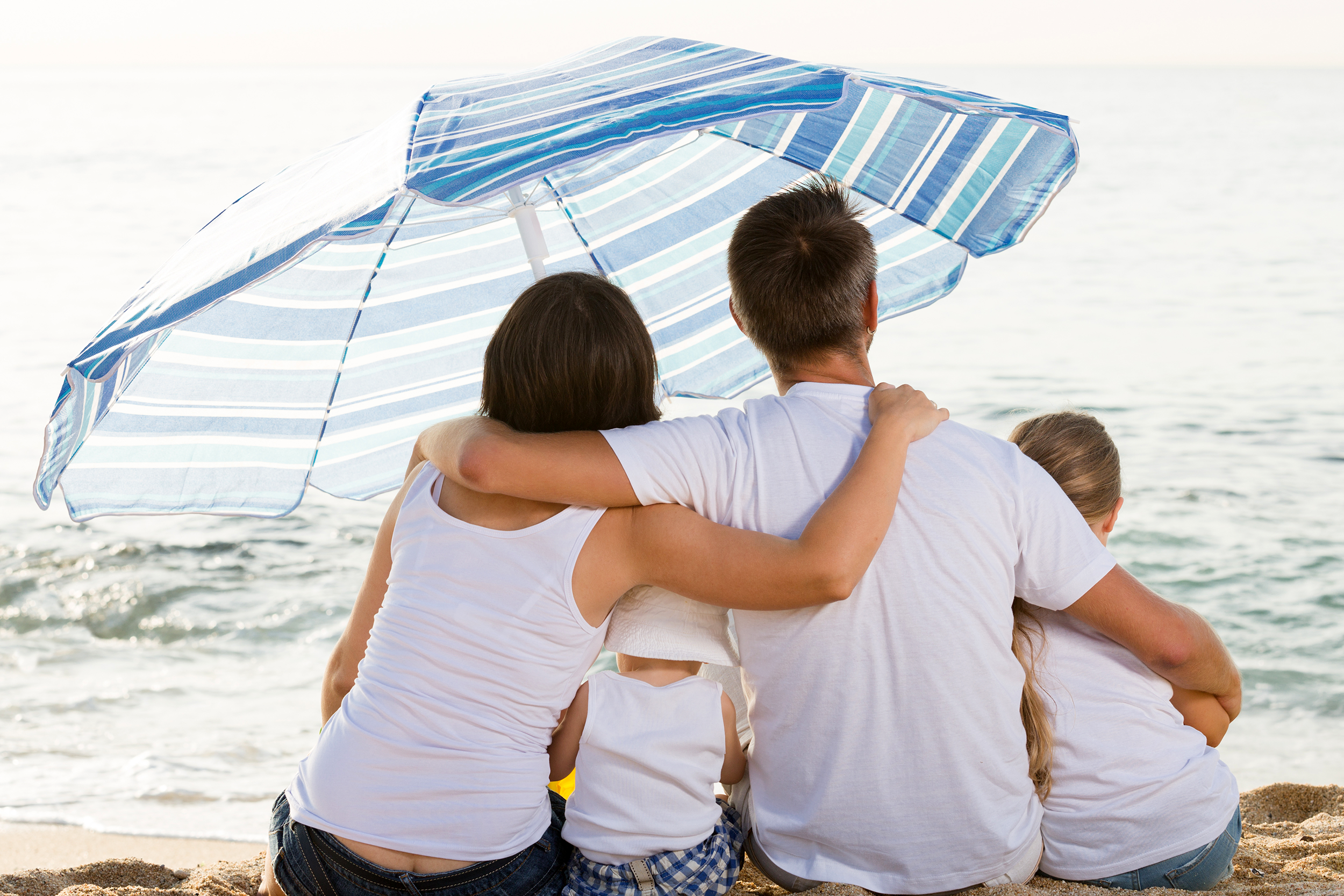 Family sitting on the beach under an umbrella