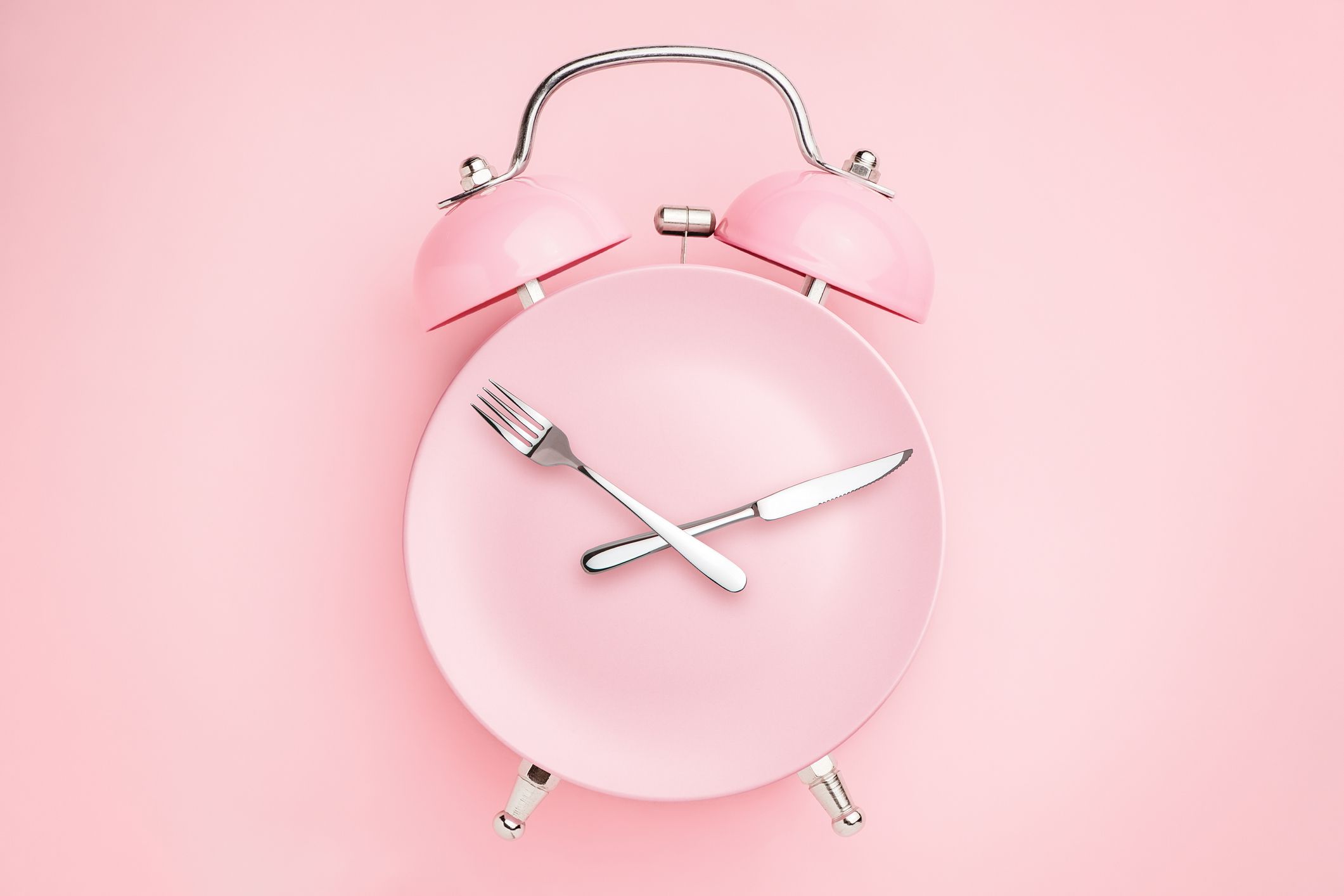 Alarm clock and plate with cutlery. Concept of intermittent fasting, lunchtime, diet and weight loss