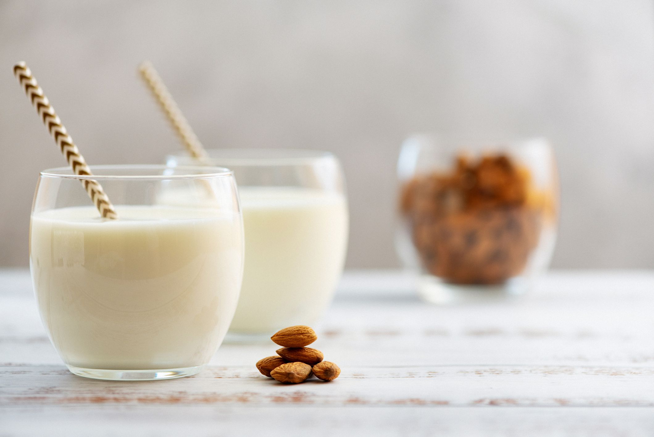 almond milk in glasses with almond on a light wooden table