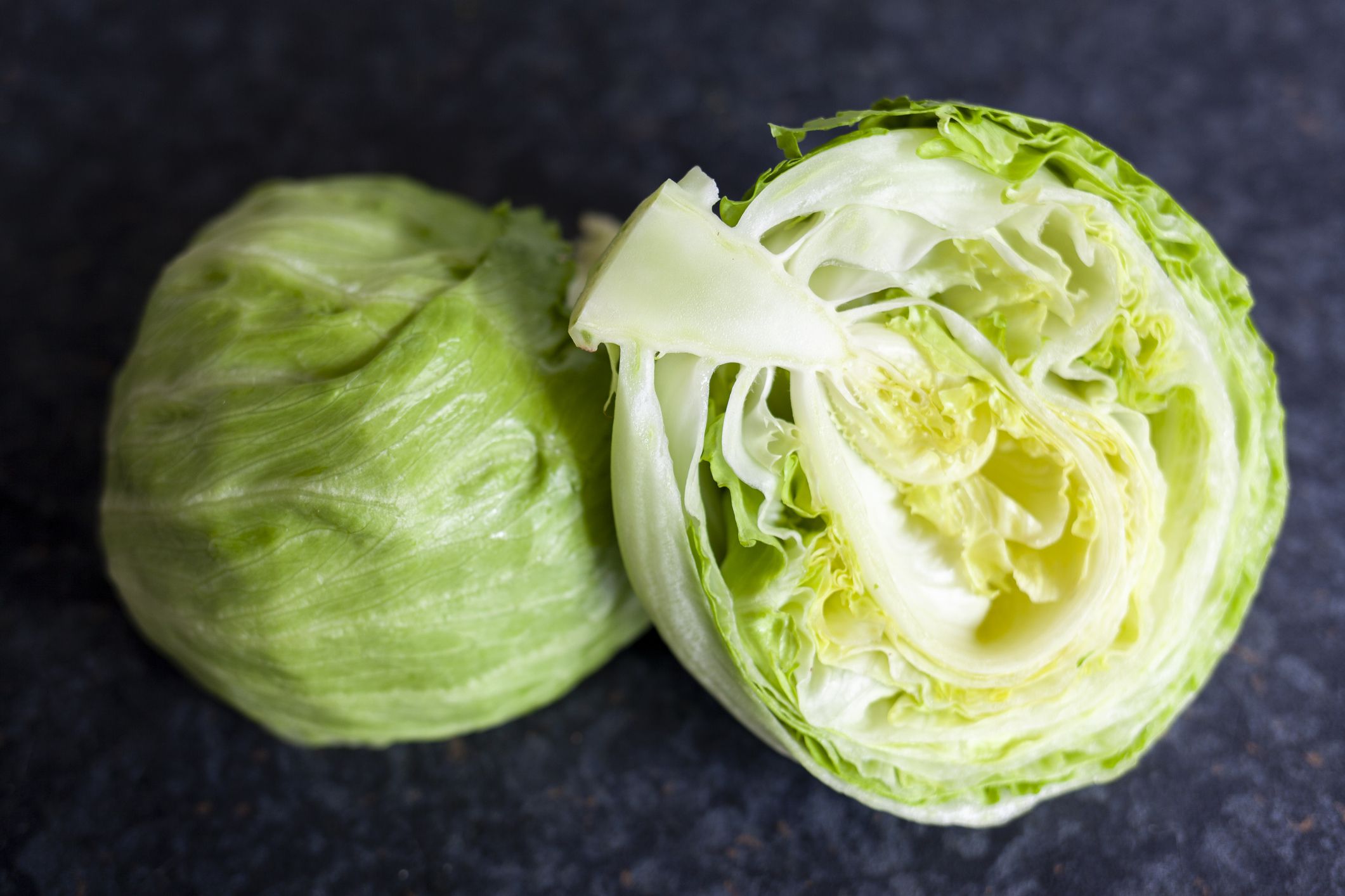 Iceberg lettuce, cut in half on a dark background
