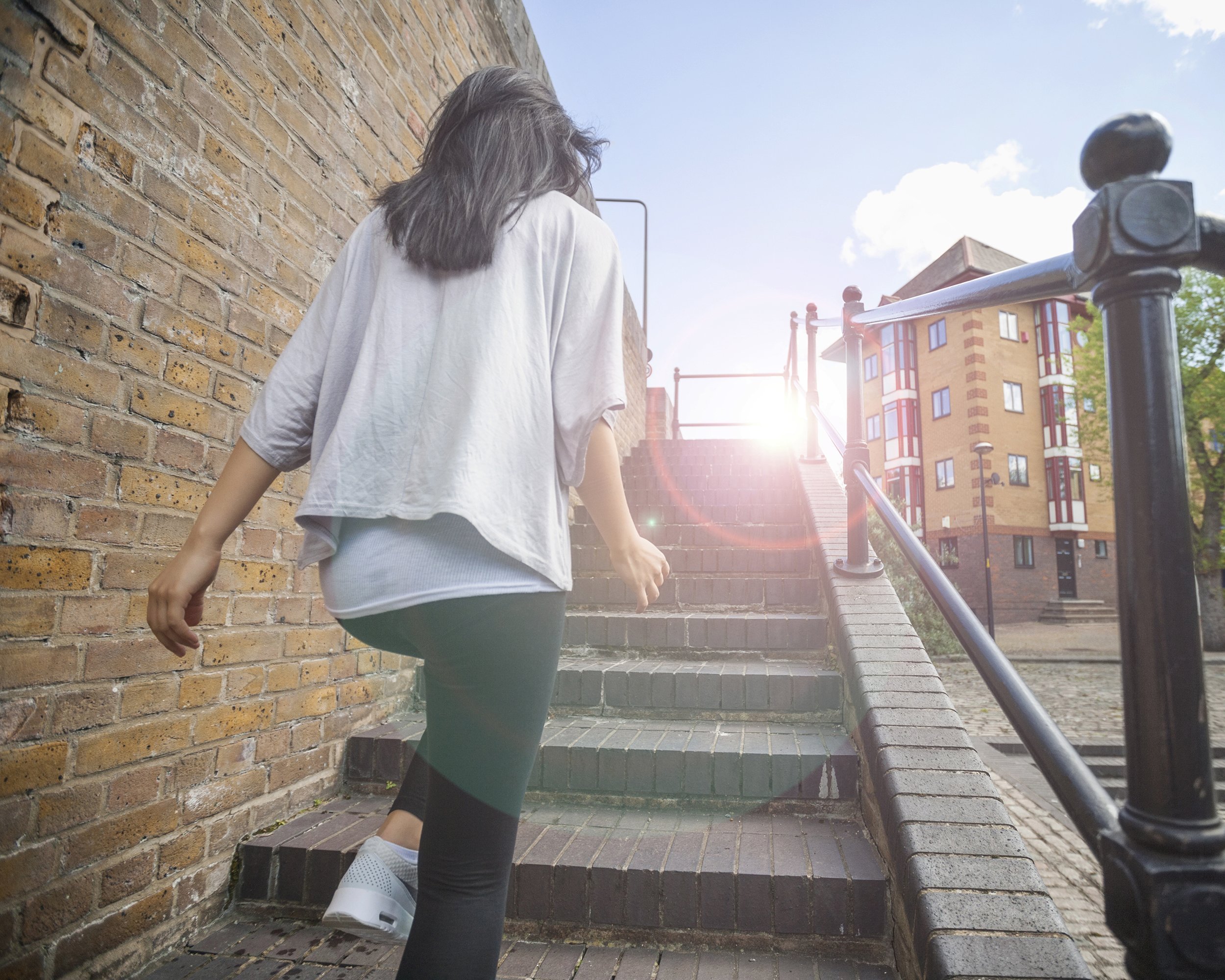 rear view of young woman walking up stairs outdoors