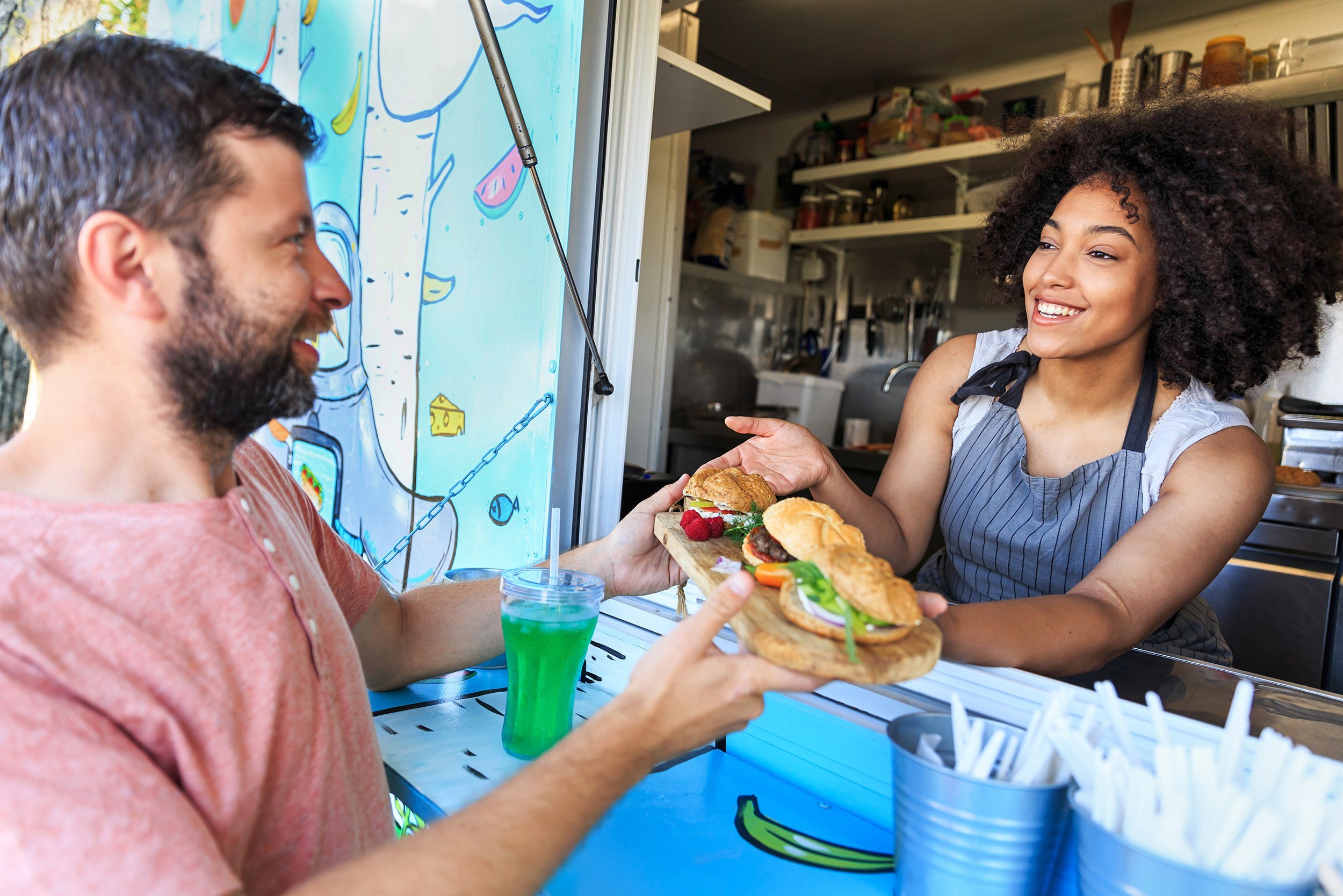 food truck owner serving sandwiches to customer