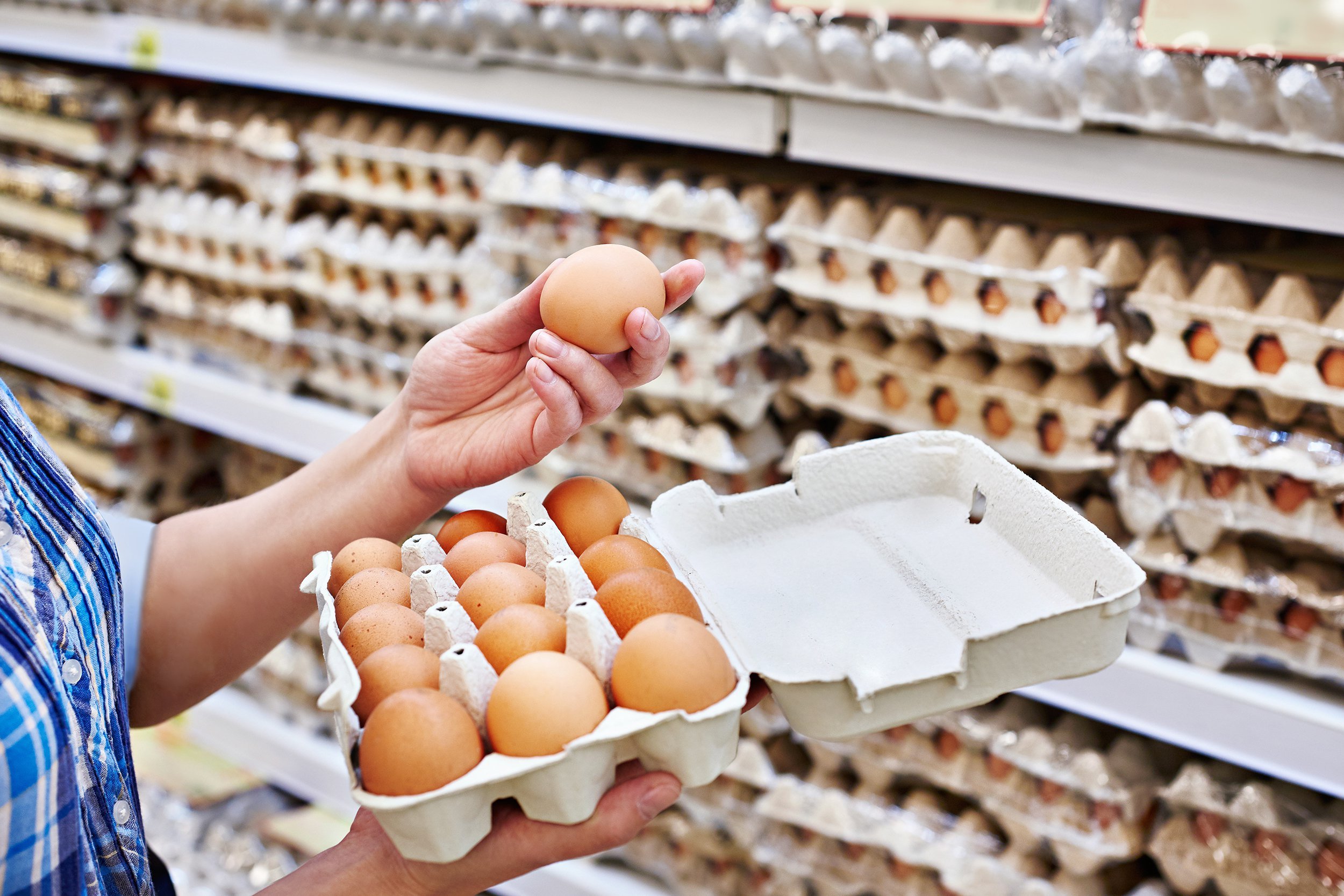 hands of woman packing eggs in supermarket