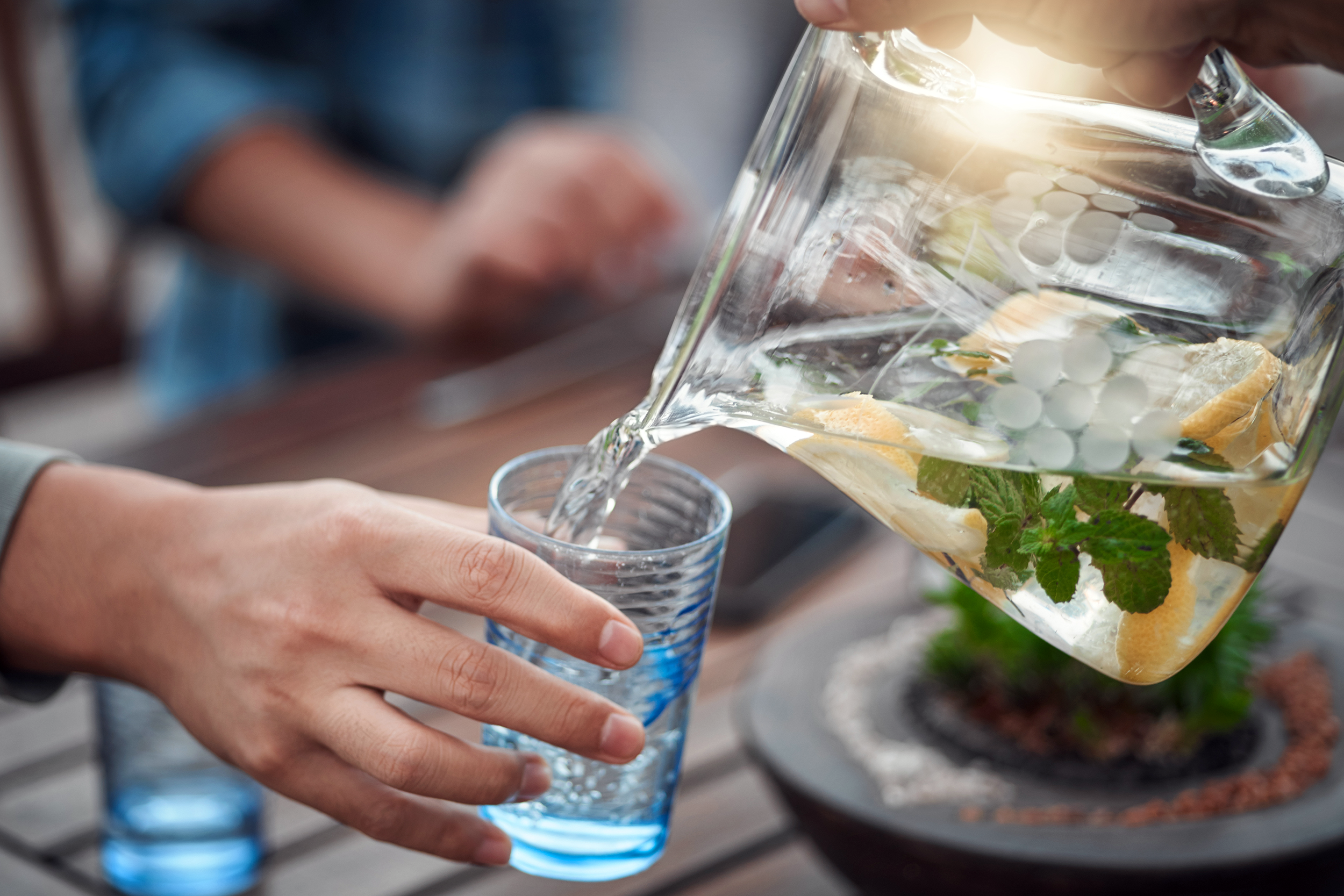 Pouring fruit-infused water into a glass at the dinner table outside