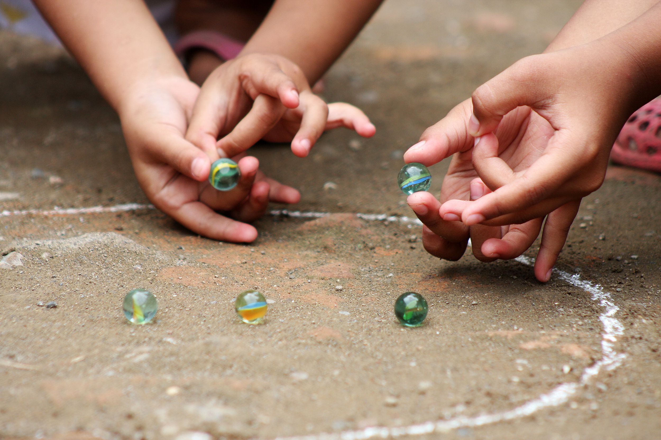 Closeup of kids playing marbles