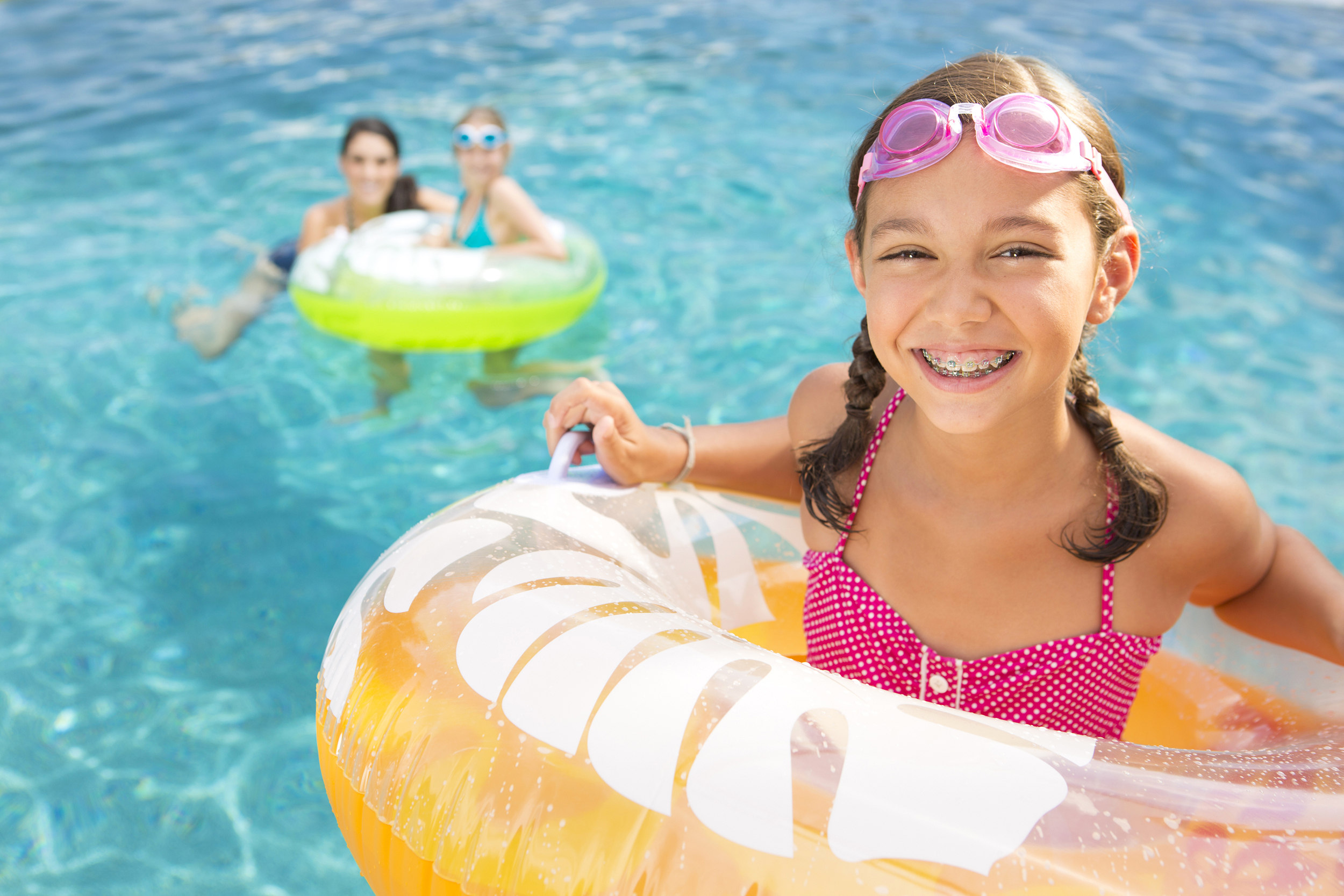 Young girl smiling in a pool float by the pool
