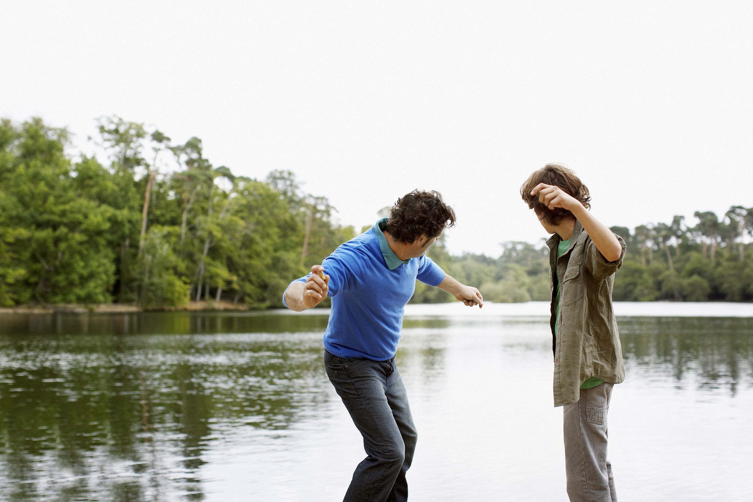 Father and son skipping rocks at the lake