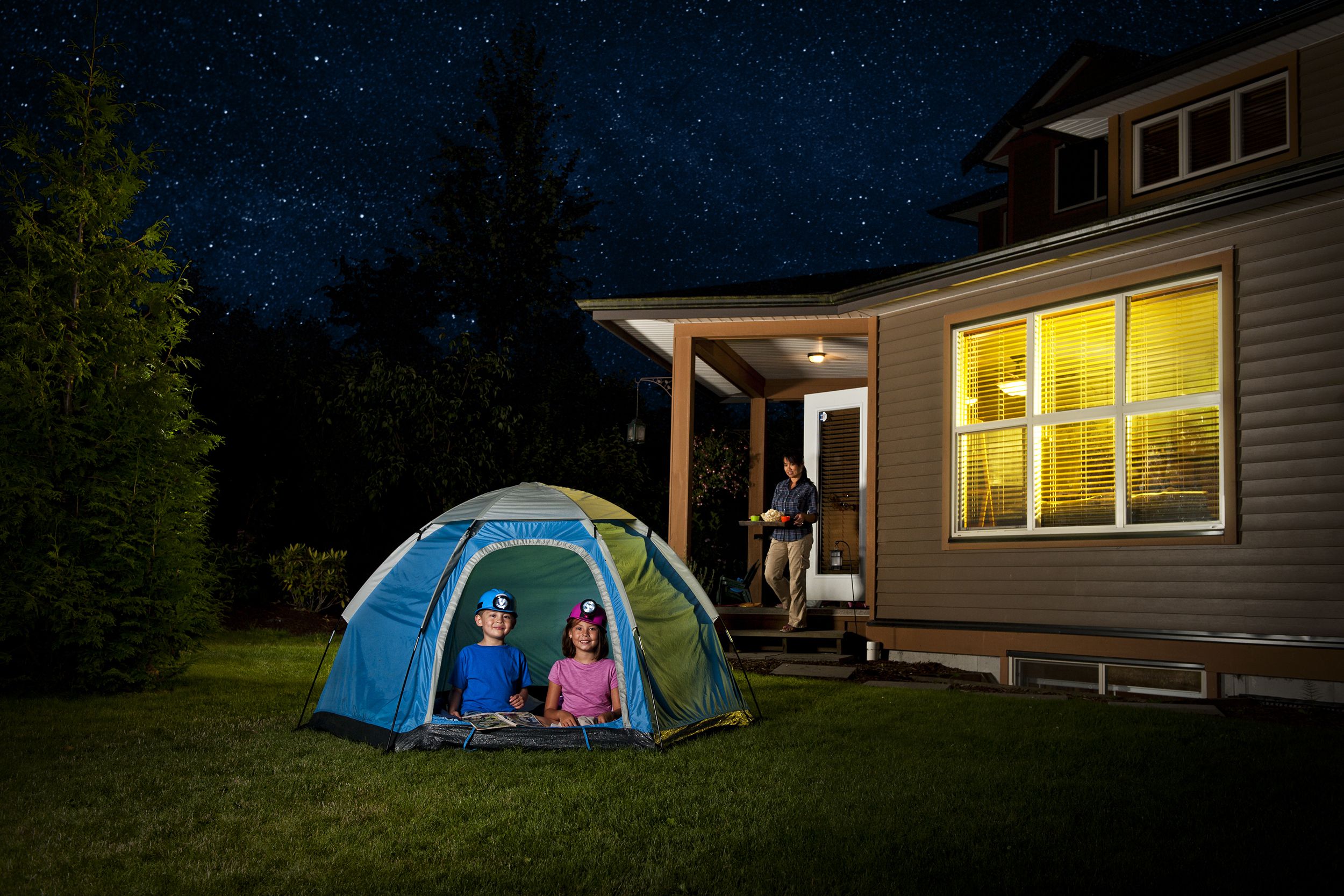 Kids playing in a tent in the backyard at night