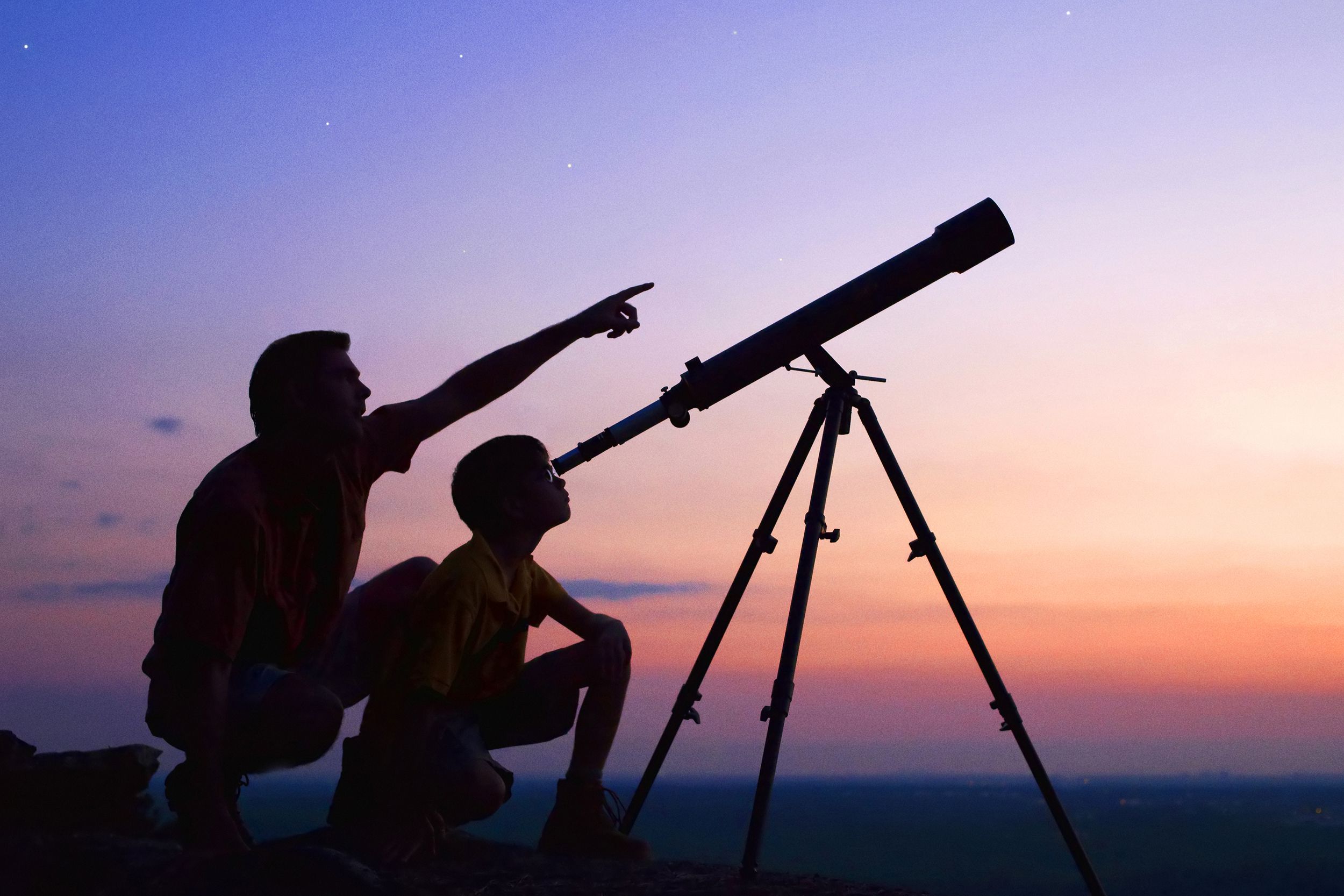 Father and son looking at the night sky with a telescope