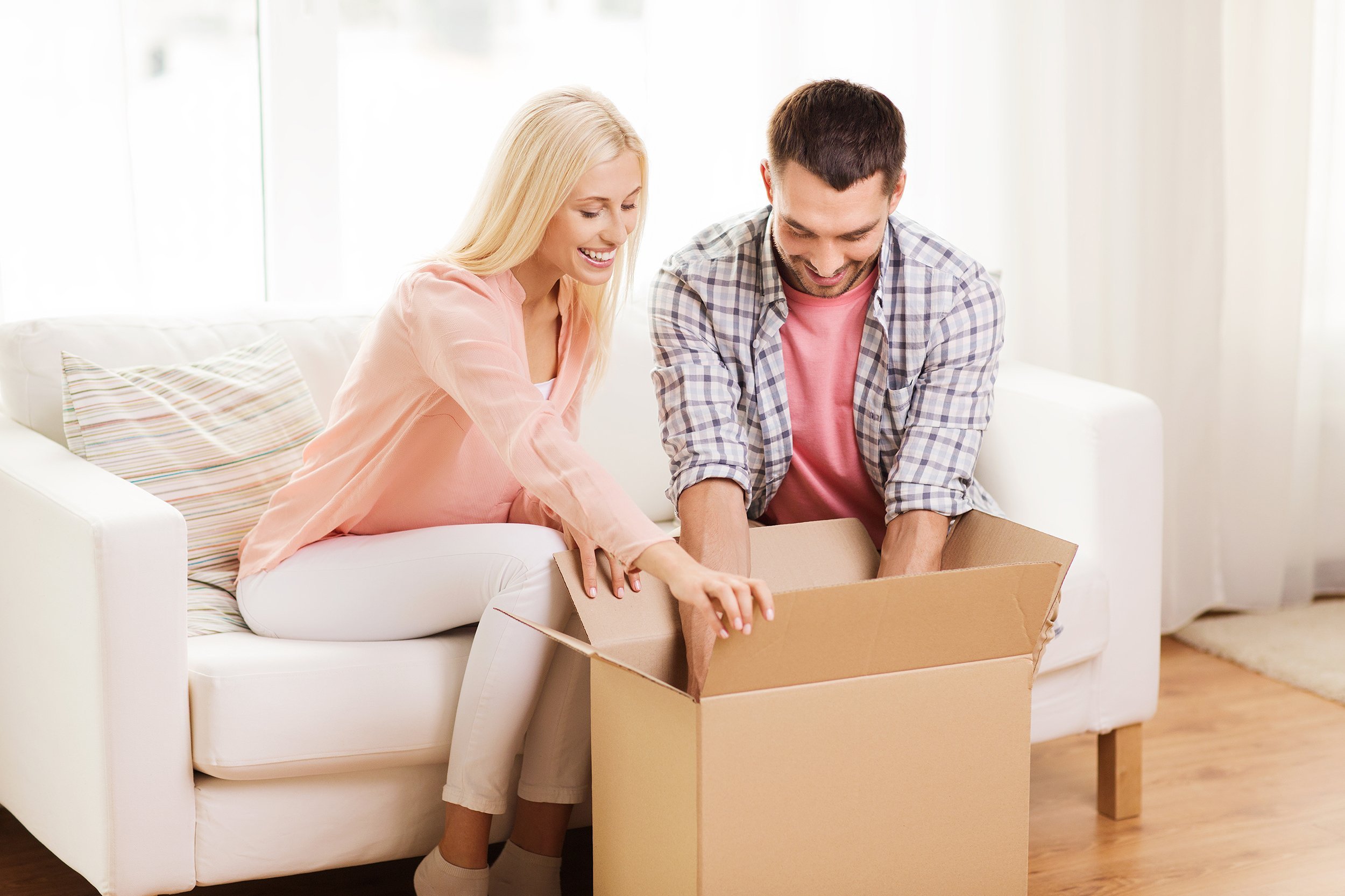 happy couple opening cardboard box or parcel at home