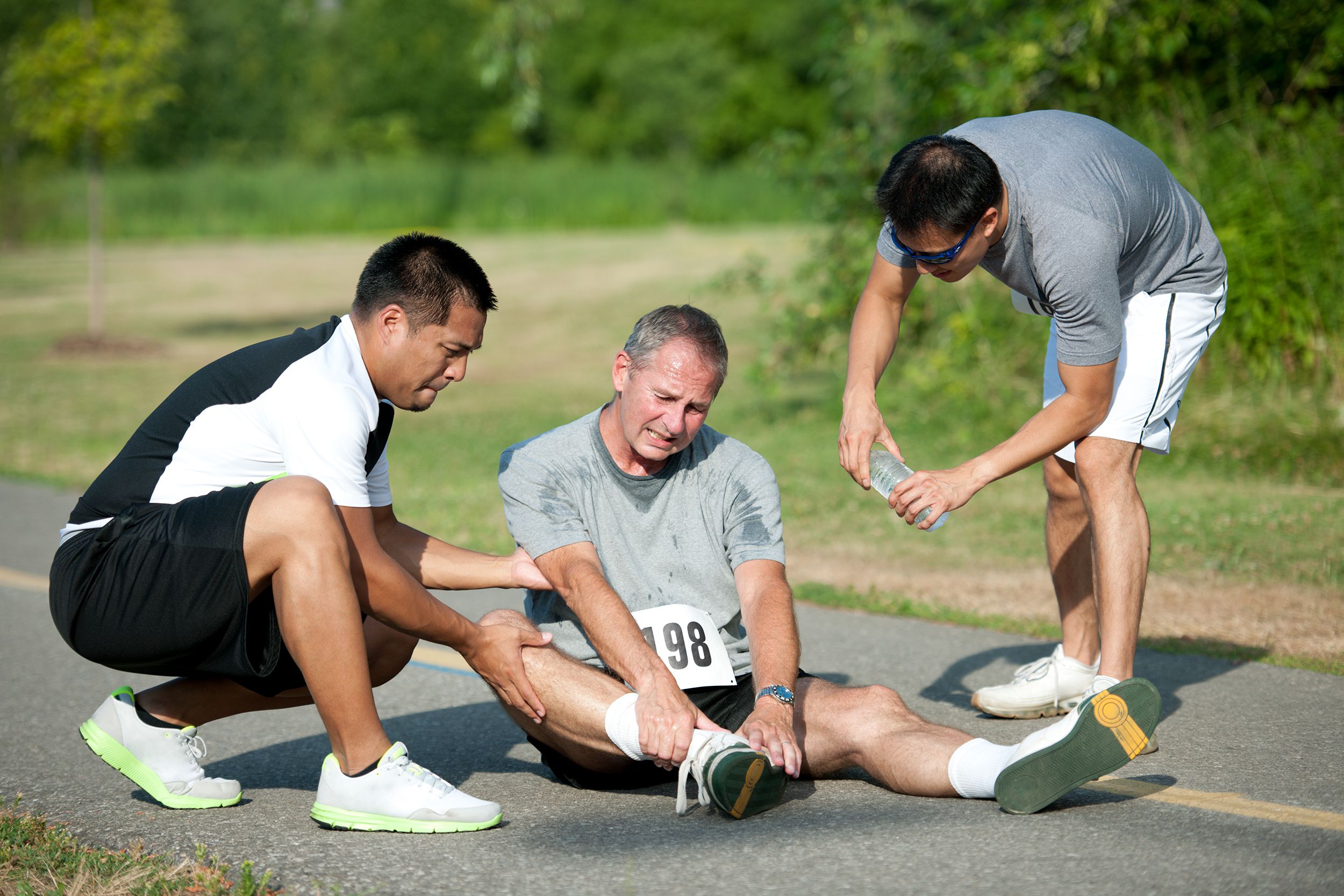 runner man with ankle sprain, two people are helping him