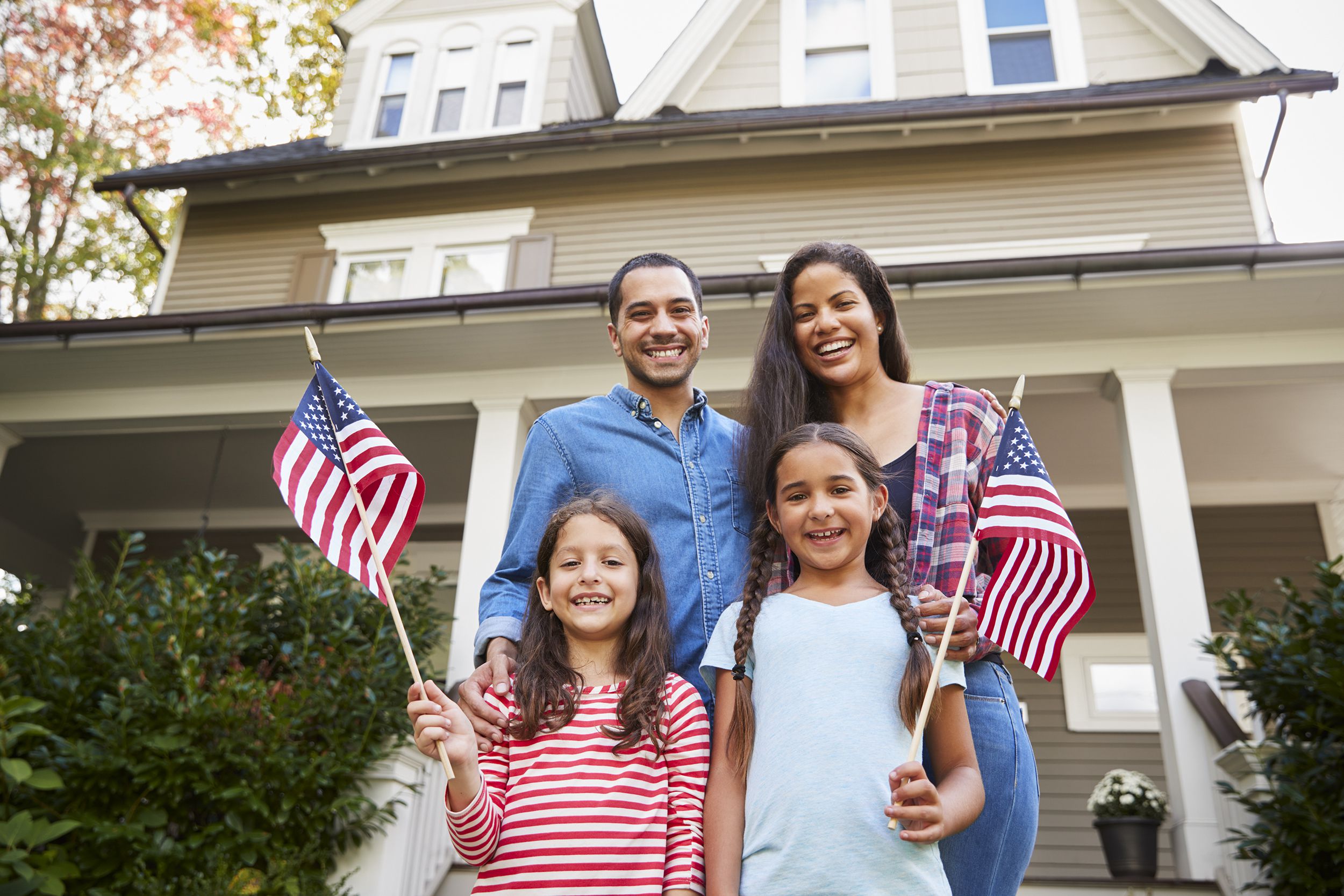 family outside house holding American Flags
