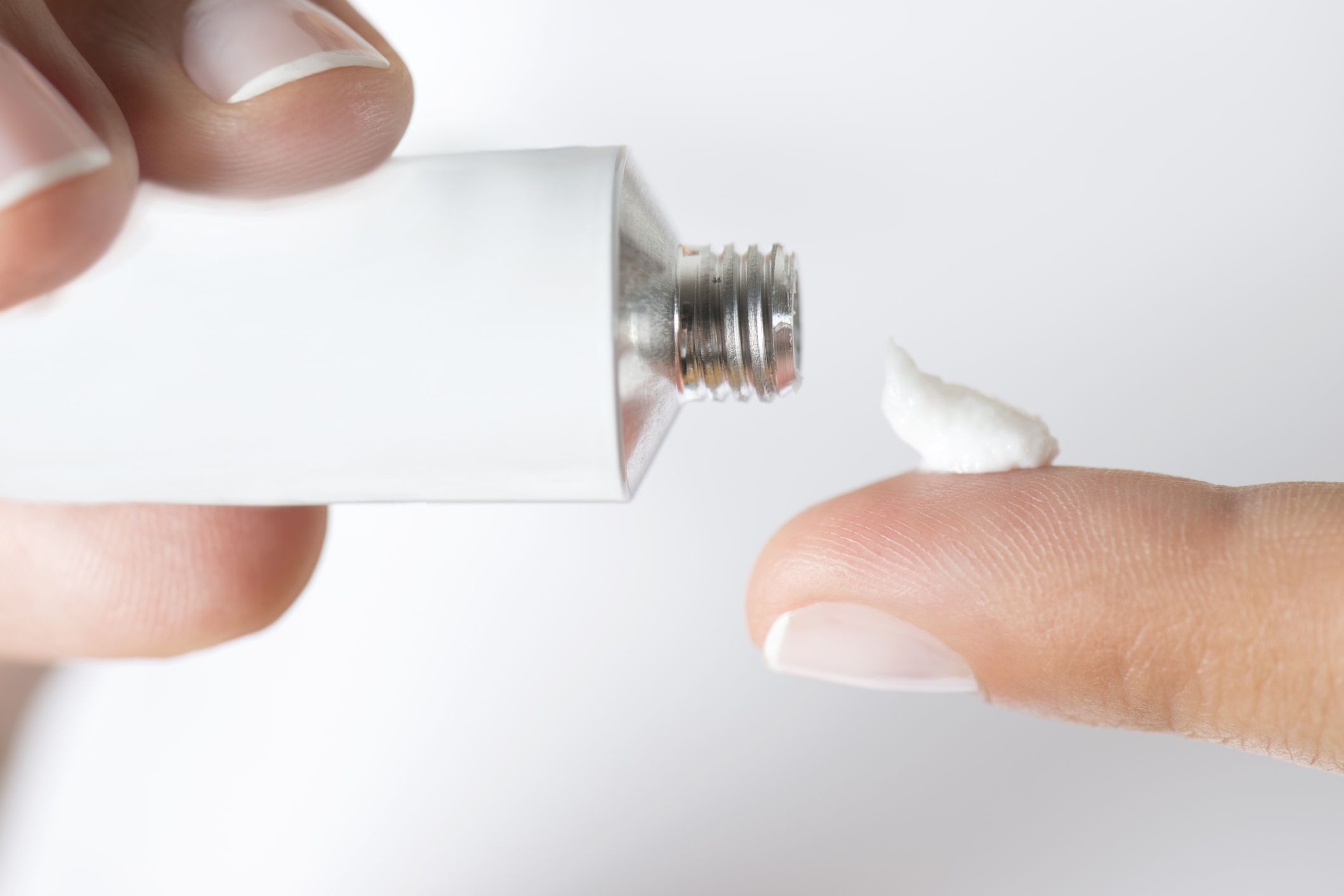 fingers applying white gel from white tube