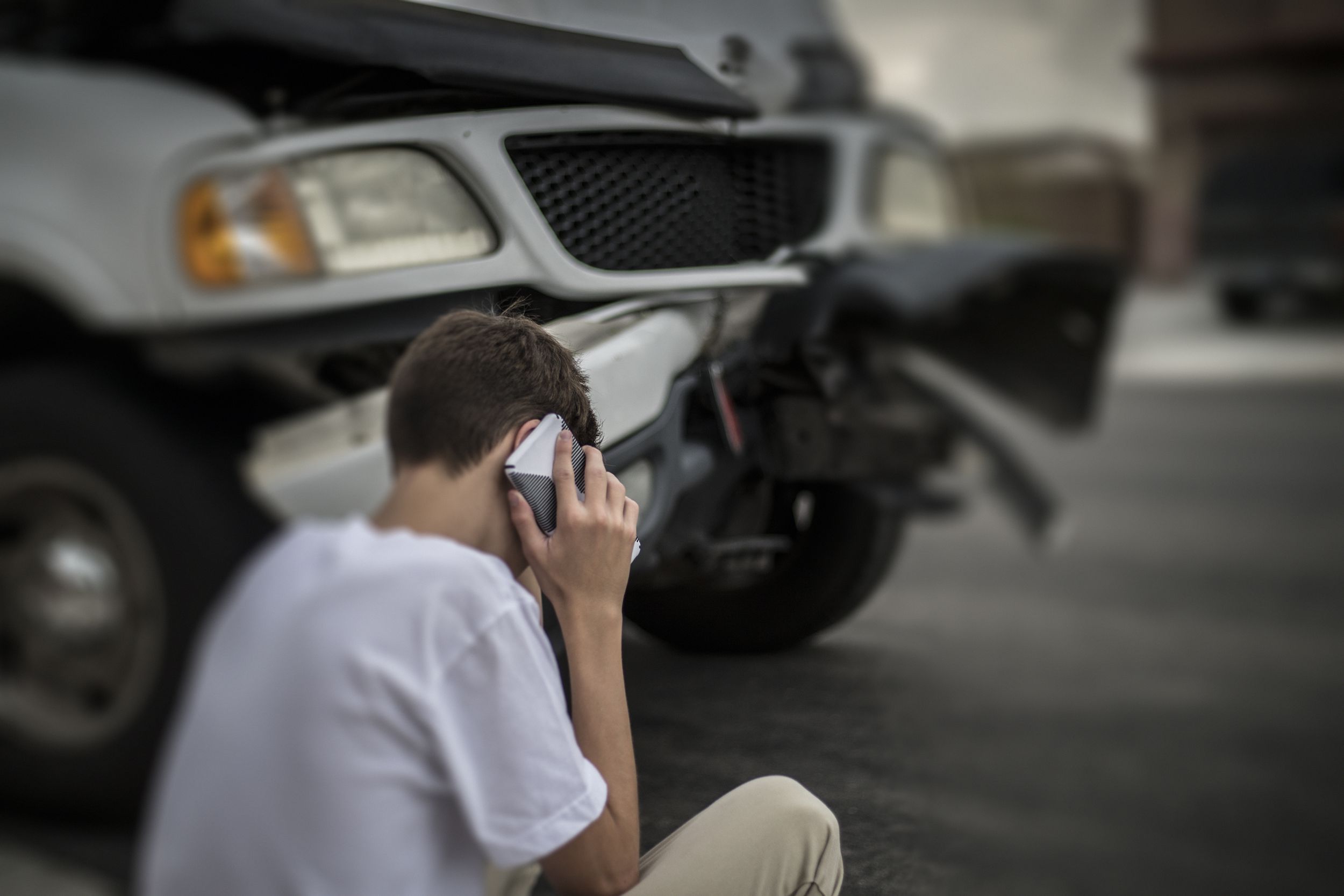 teen on phone in front of car accident