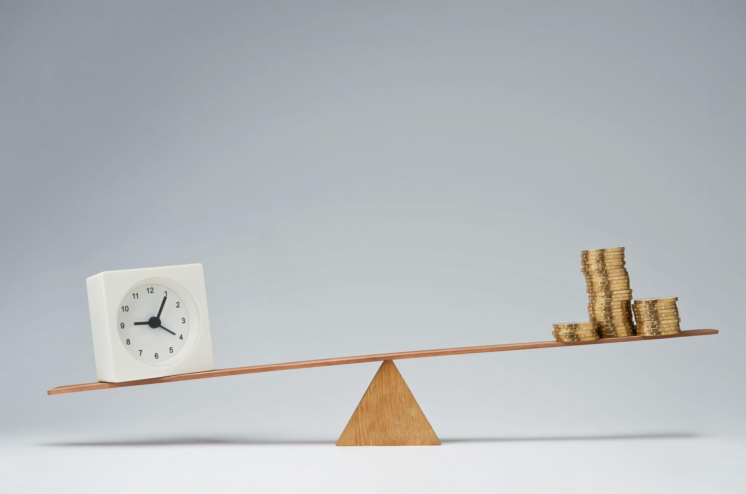 clock and money coins stack balancing on a seesaw