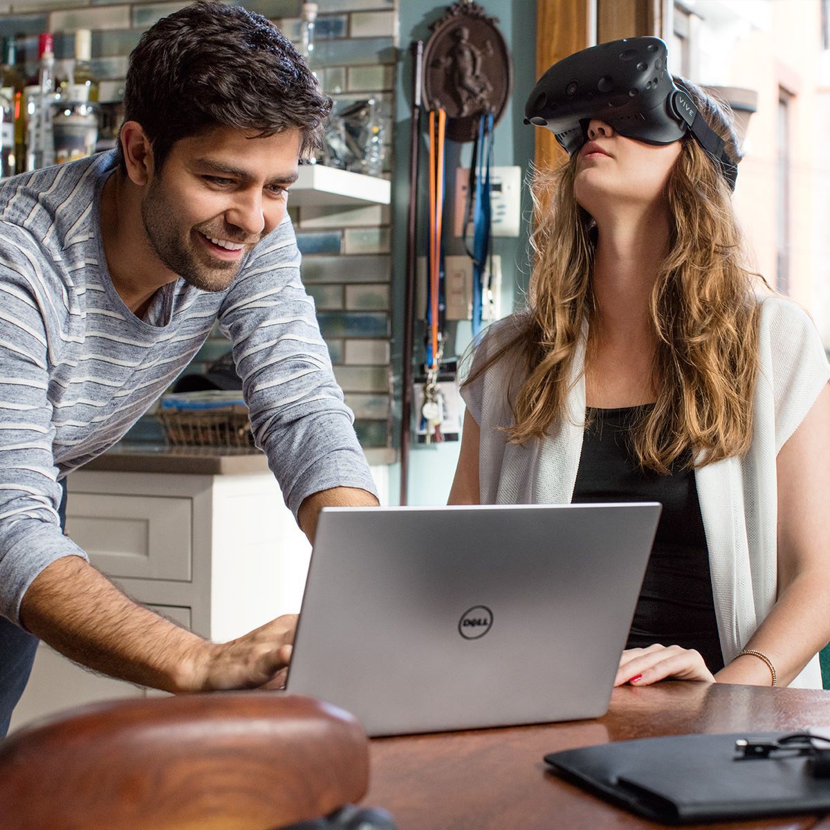 Two young adults using a Dell laptop and VR goggles