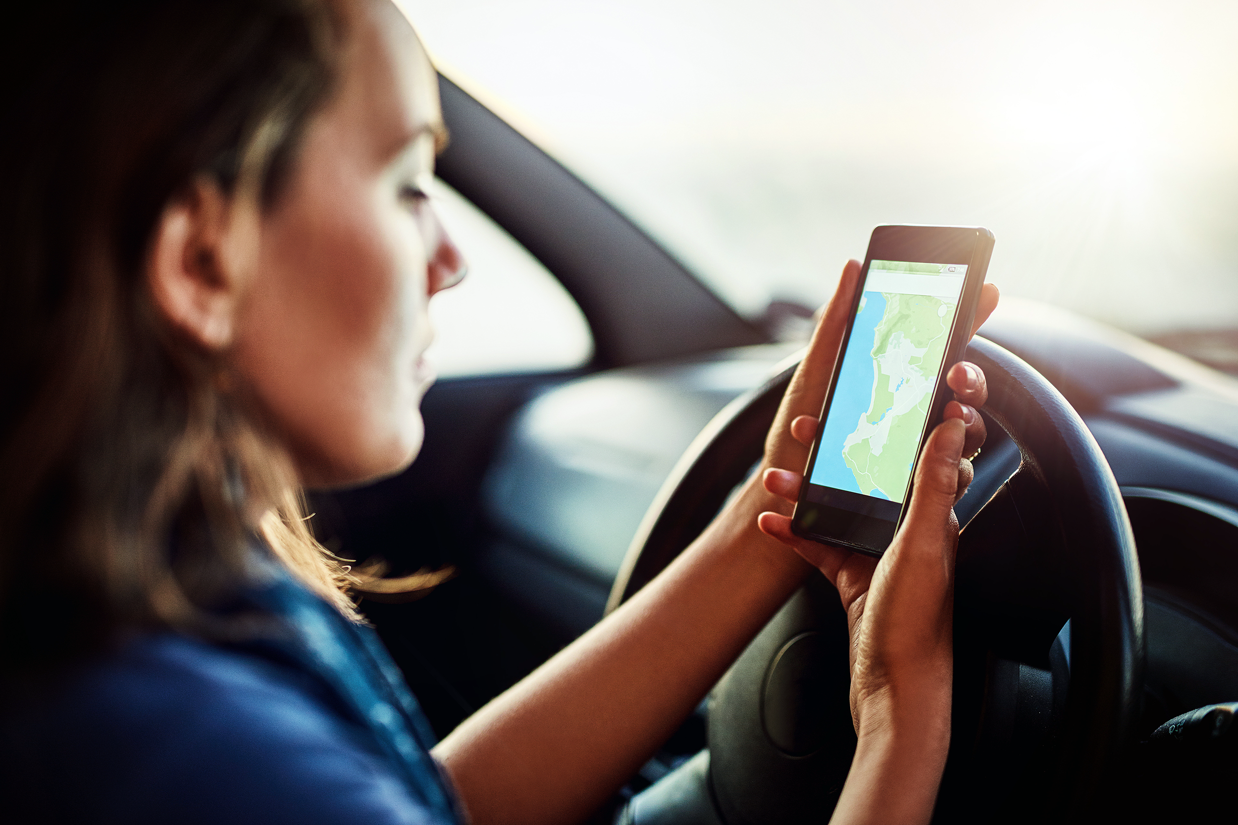 Driver looking at GPS navigation on her phone