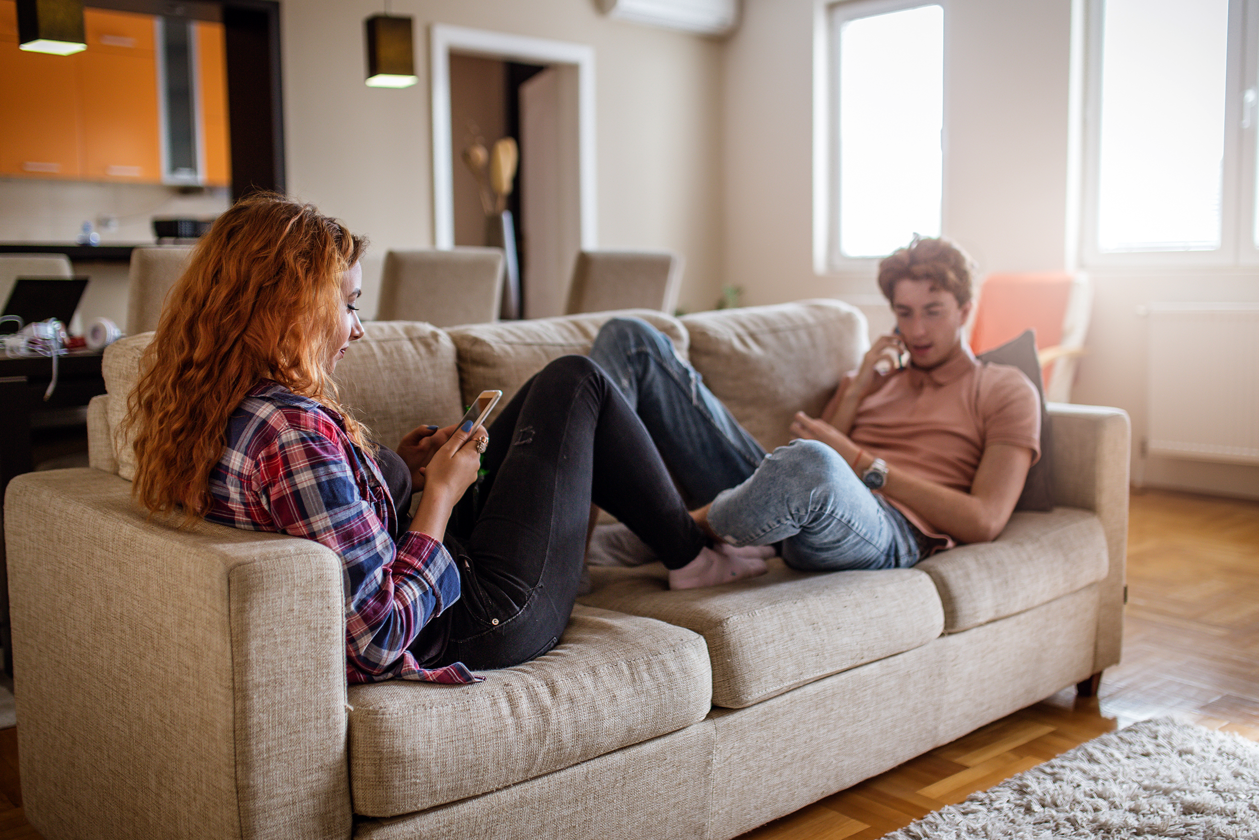 Teenagers lounging on the couch using their phones