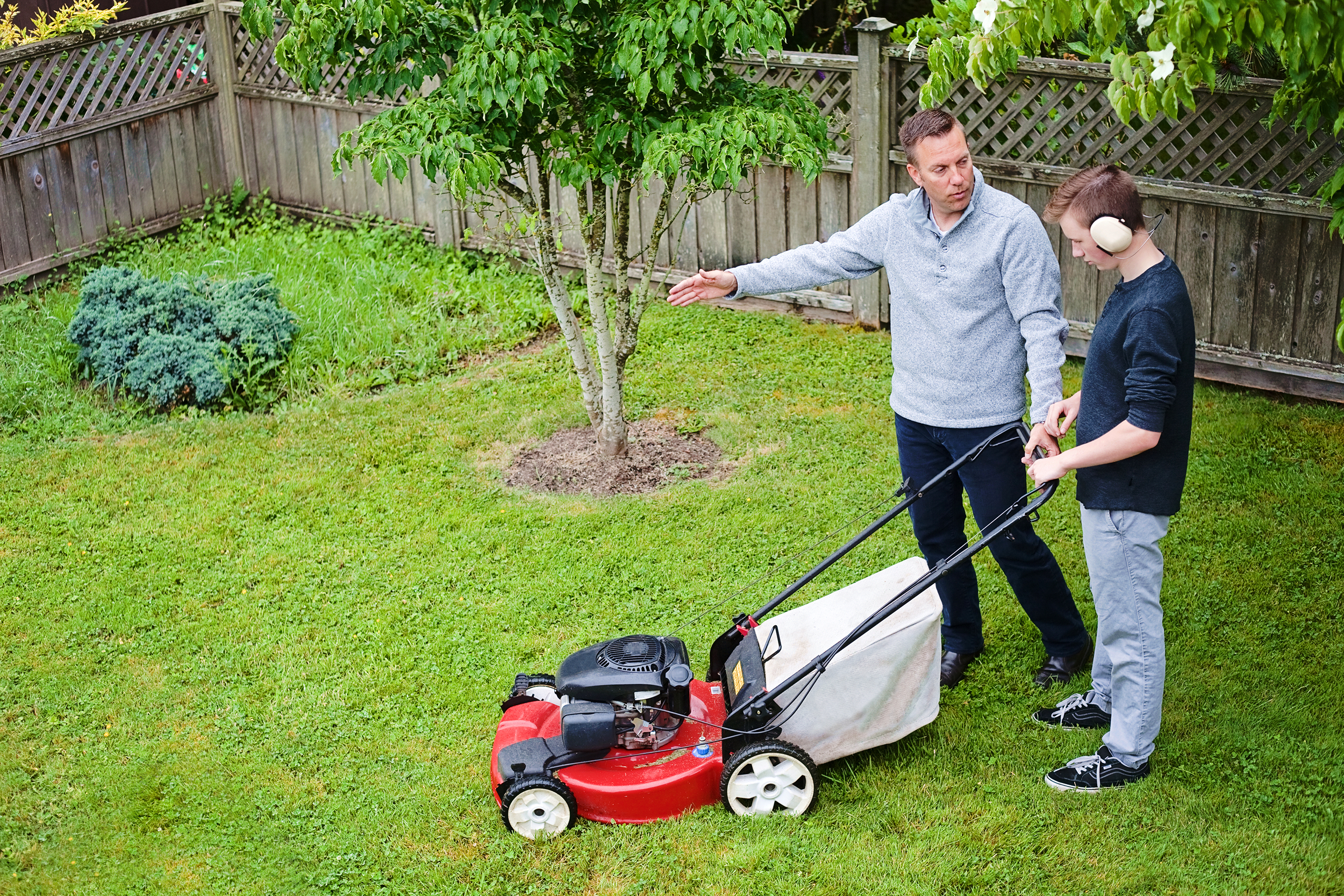 Dad showing son how to mow the lawn