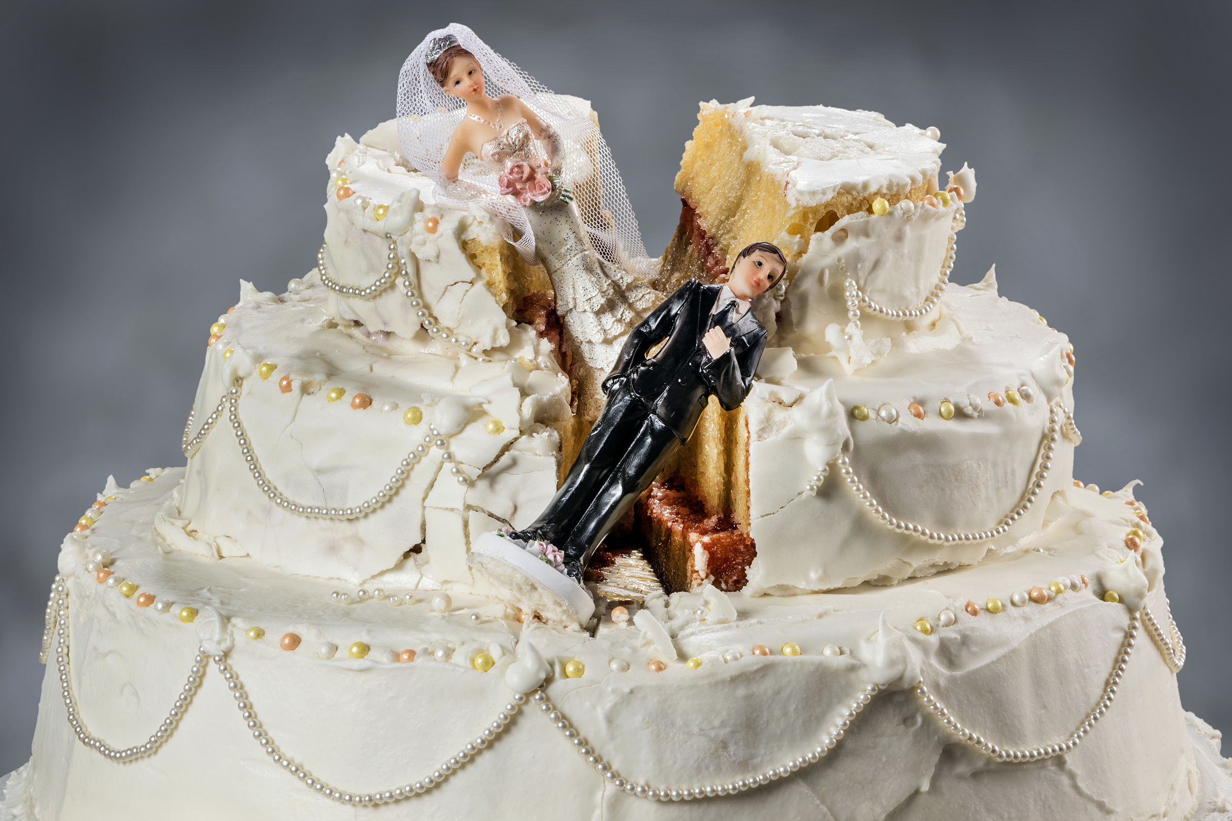 Cracked wedding cake with bride and groom toppers