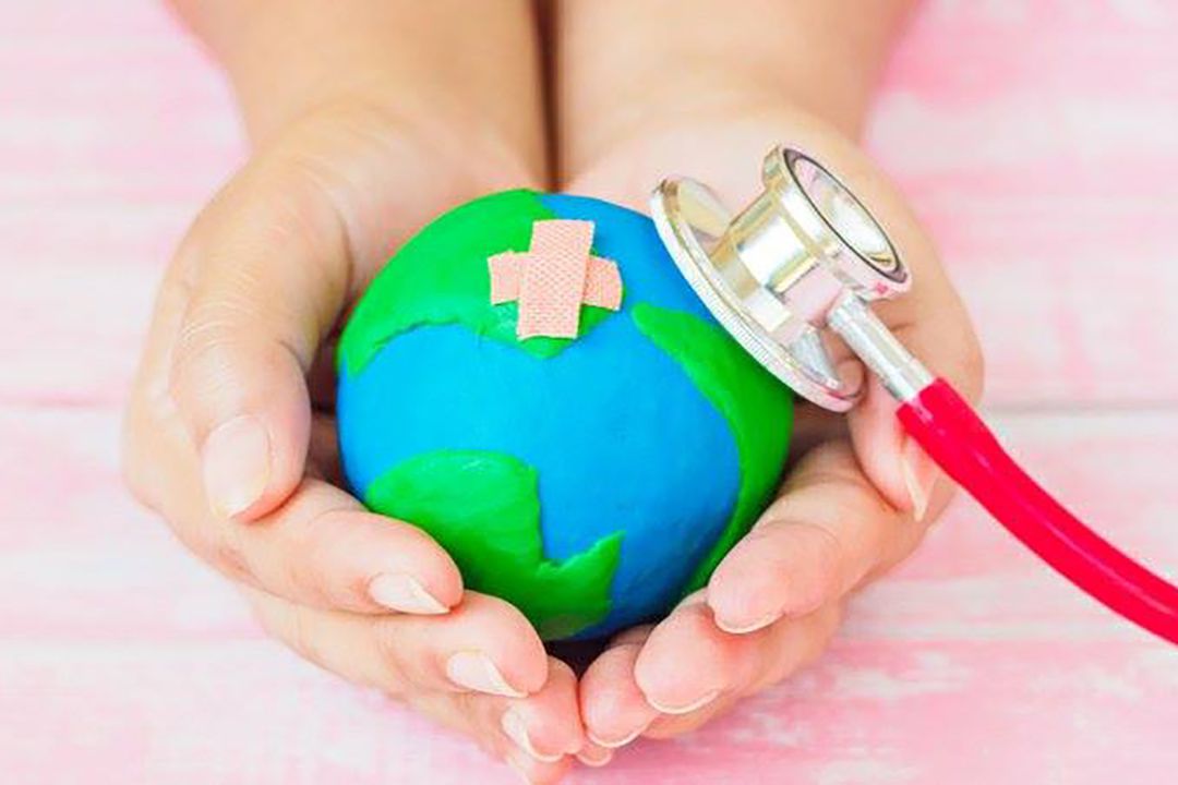 Hands holding a tiny earth and stethoscope
