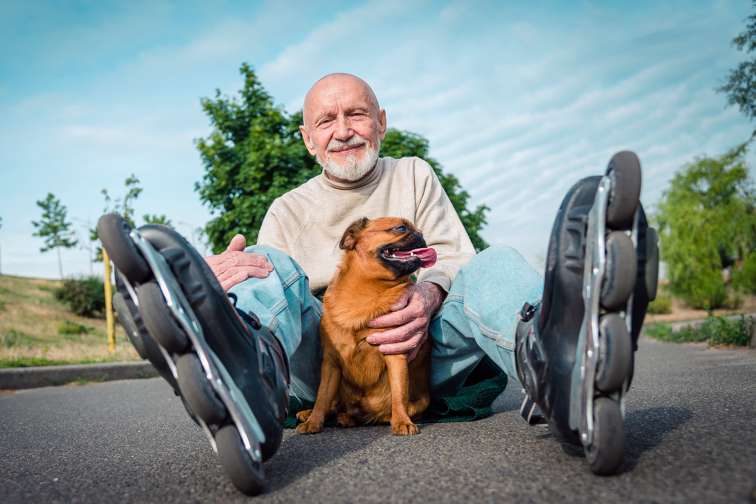 Man wearing rollerblades sitting with his dog