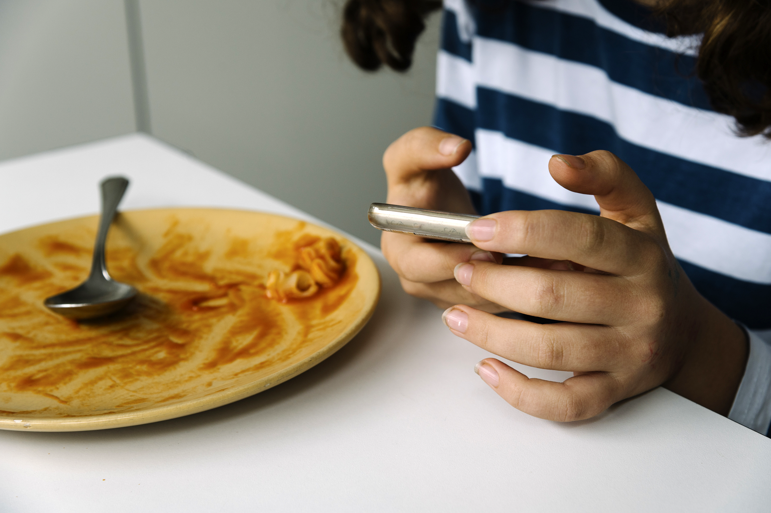 Teen at the dinner table looking at her phone