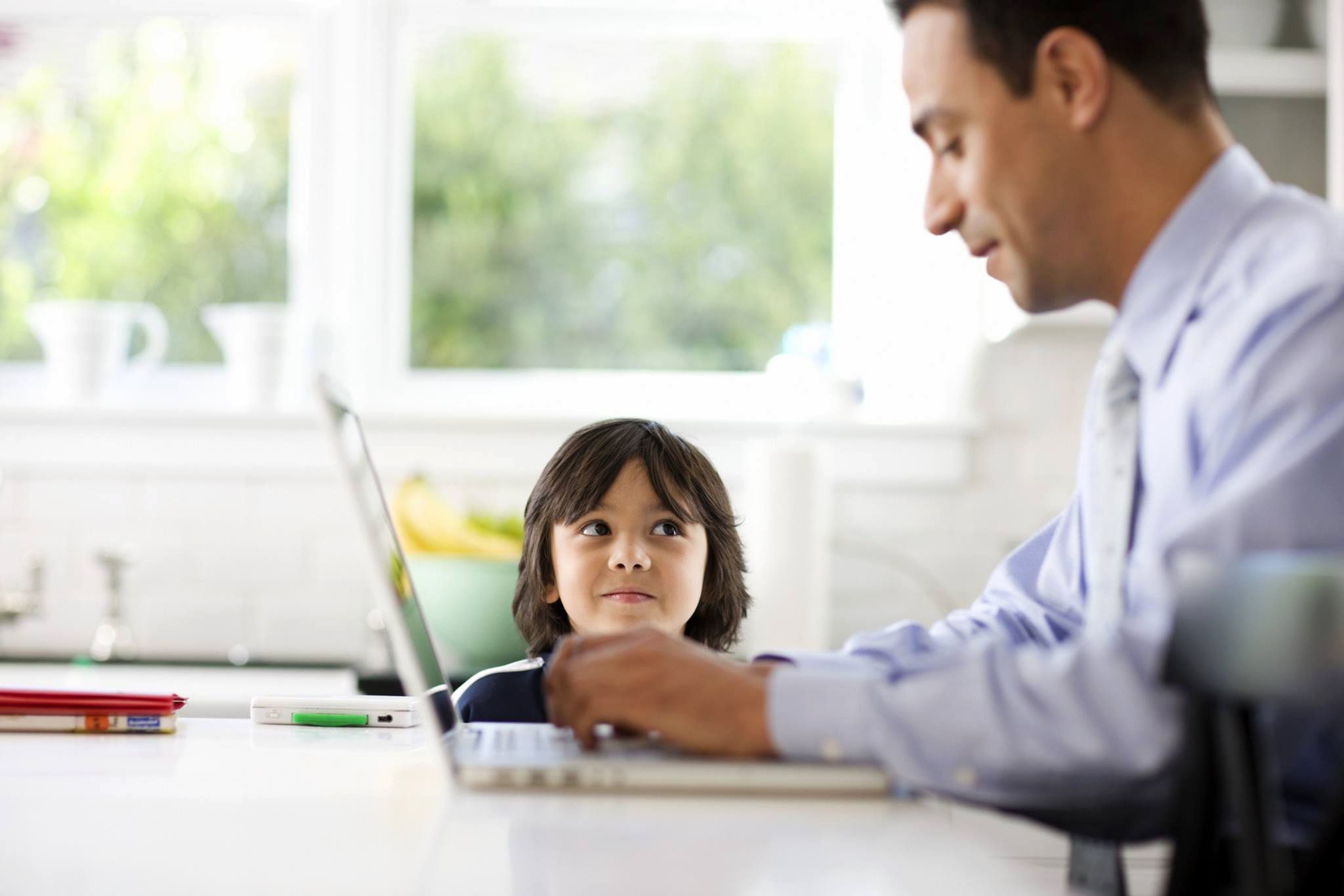 Young child looking at his dad working from home