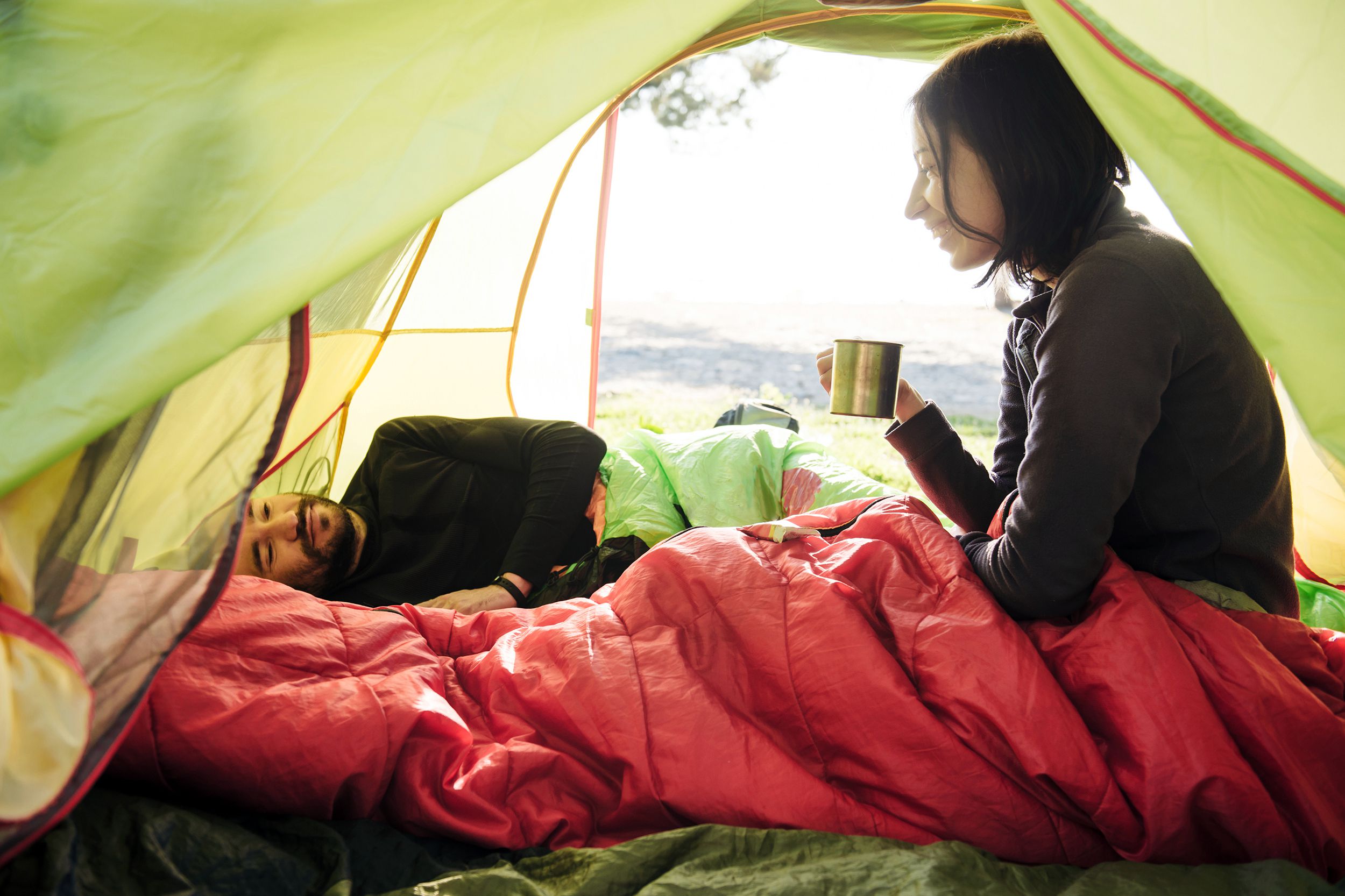 couple wrapped up in sleeping bags in tent