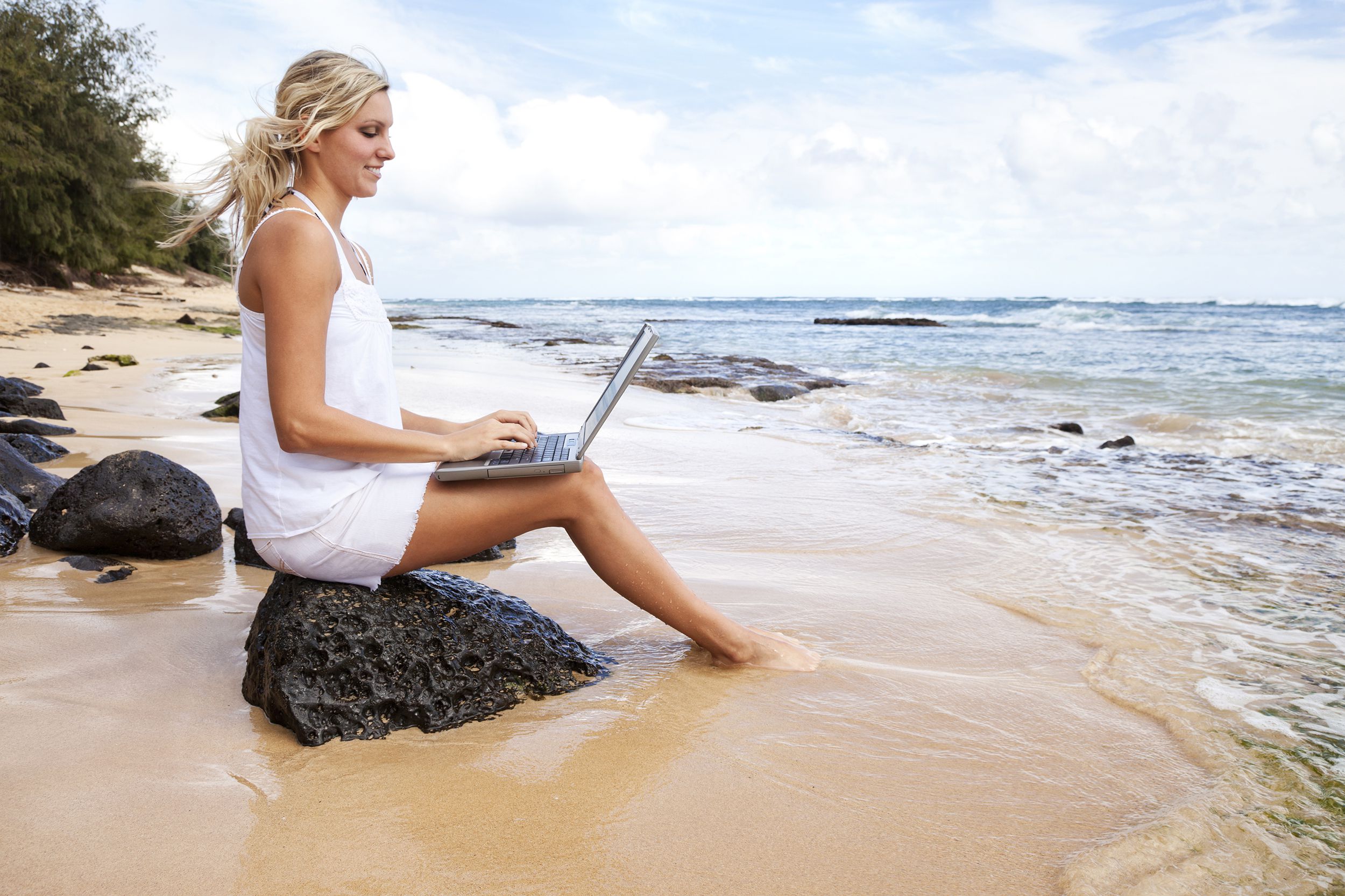 woman on beach with laptop on Hawaiian beach