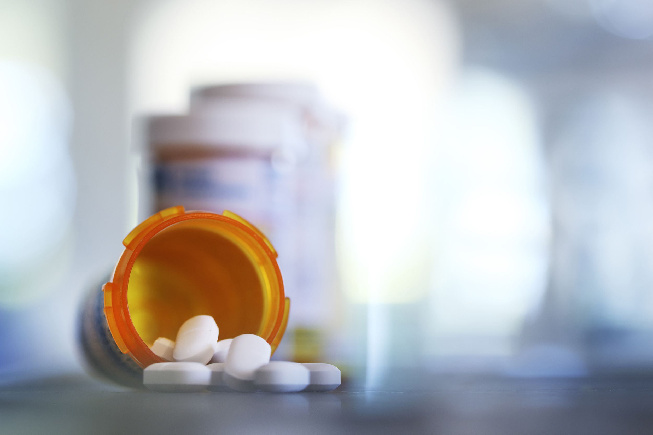 pills pour out of prescription medication bottle onto kitchen counter