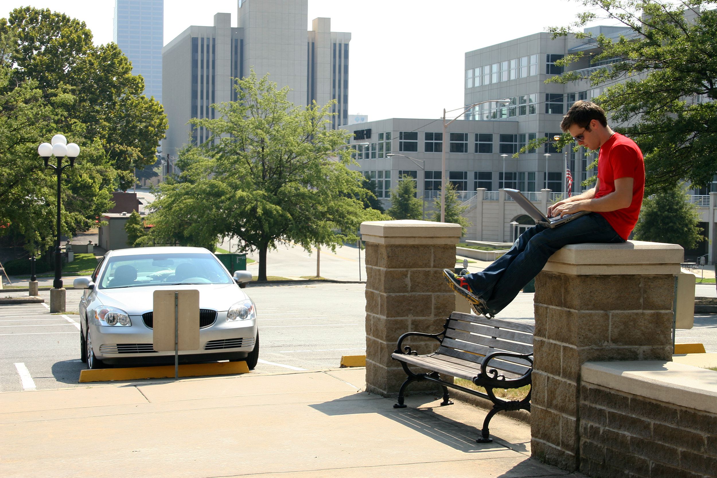 man sitting on wall with laptop in Little Rock, Arkansas