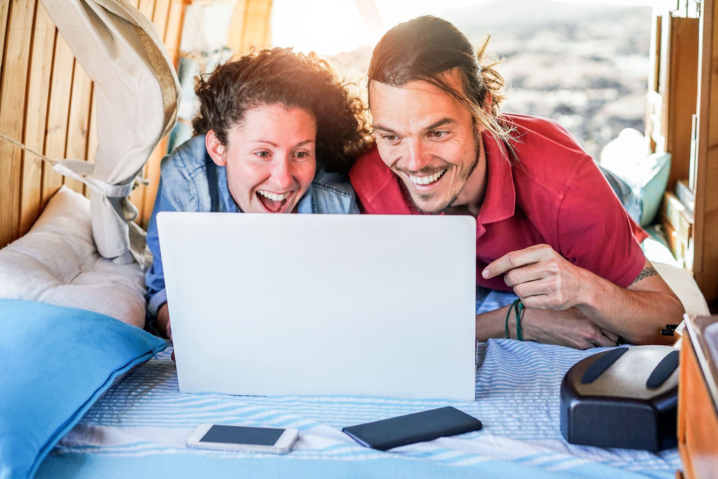 couple watching videos on laptop computer inside minivan at sunset