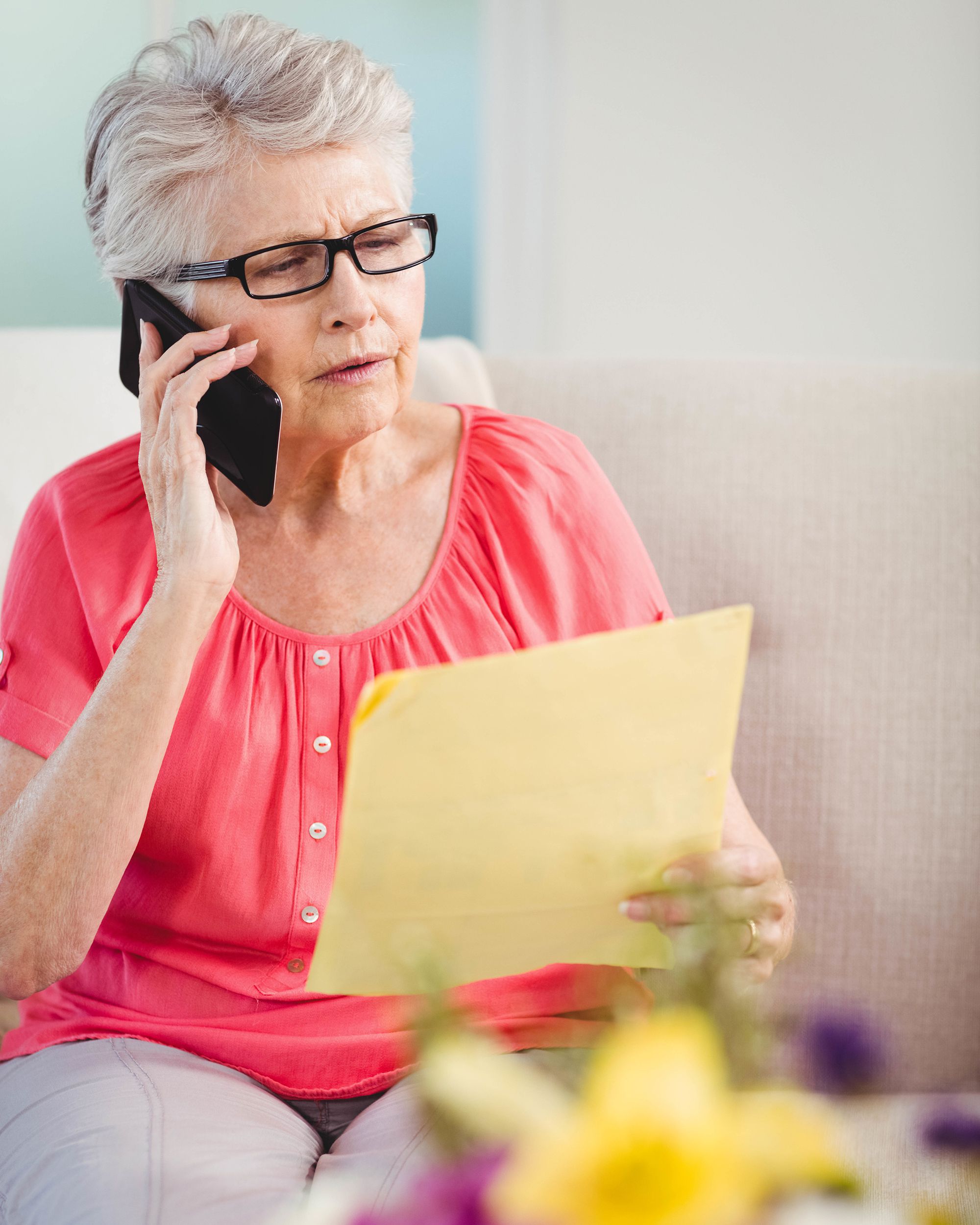 senior woman reading a letter and talking on phone