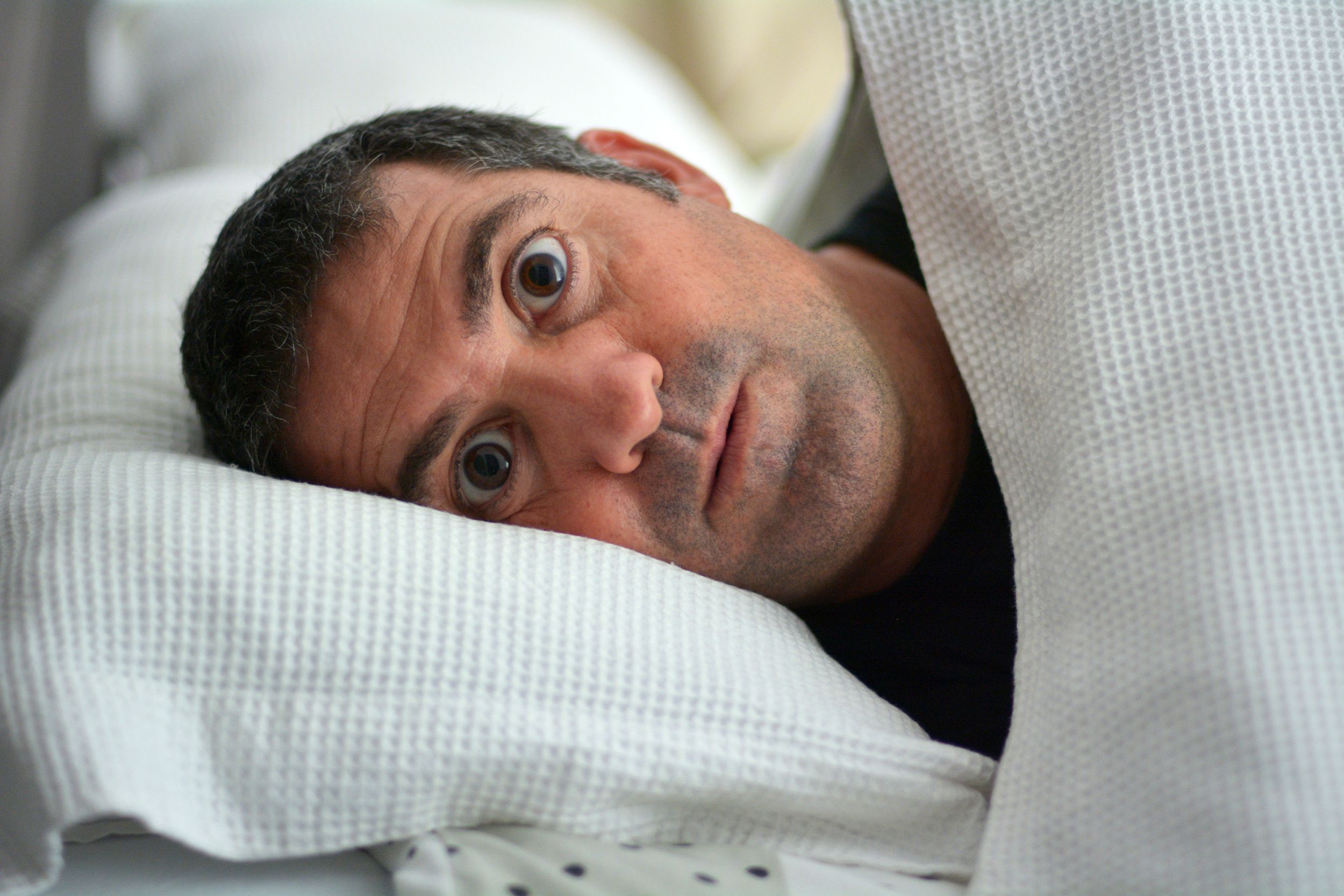 scared, sleepless man in bed