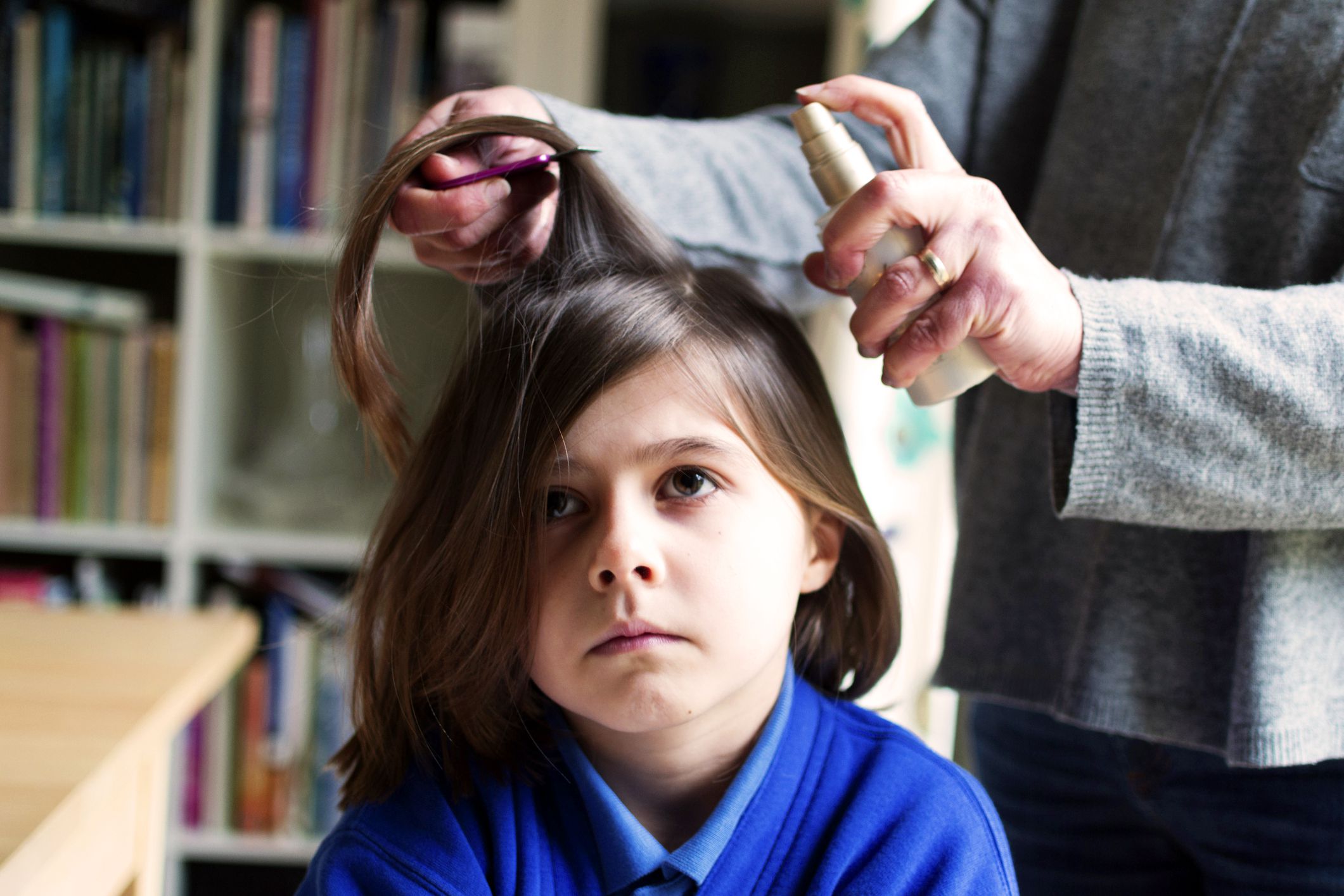 little girl receiving head lice spray treatment