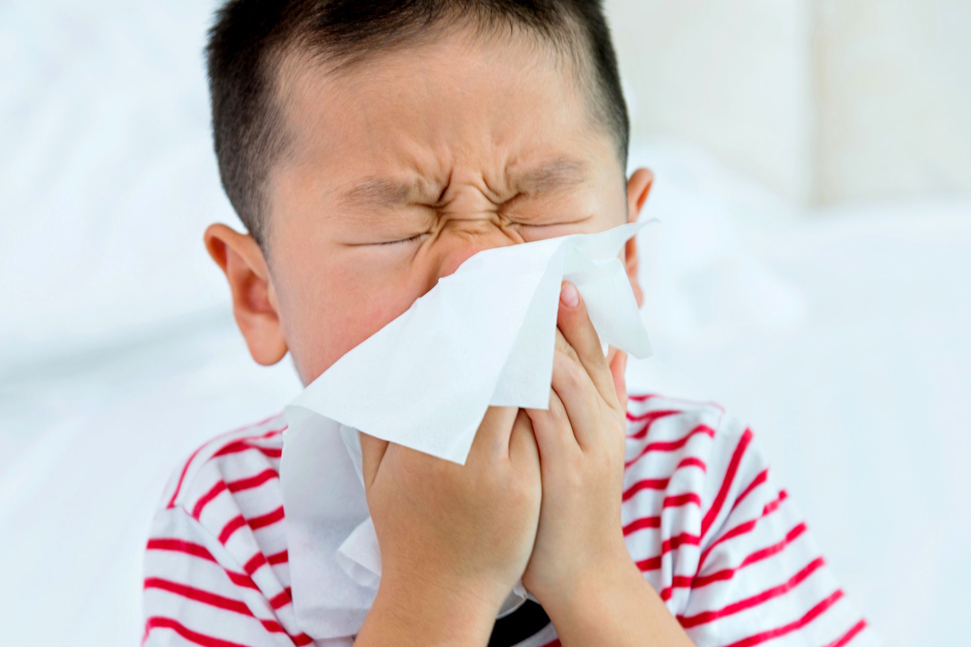 child sneezing into tissue
