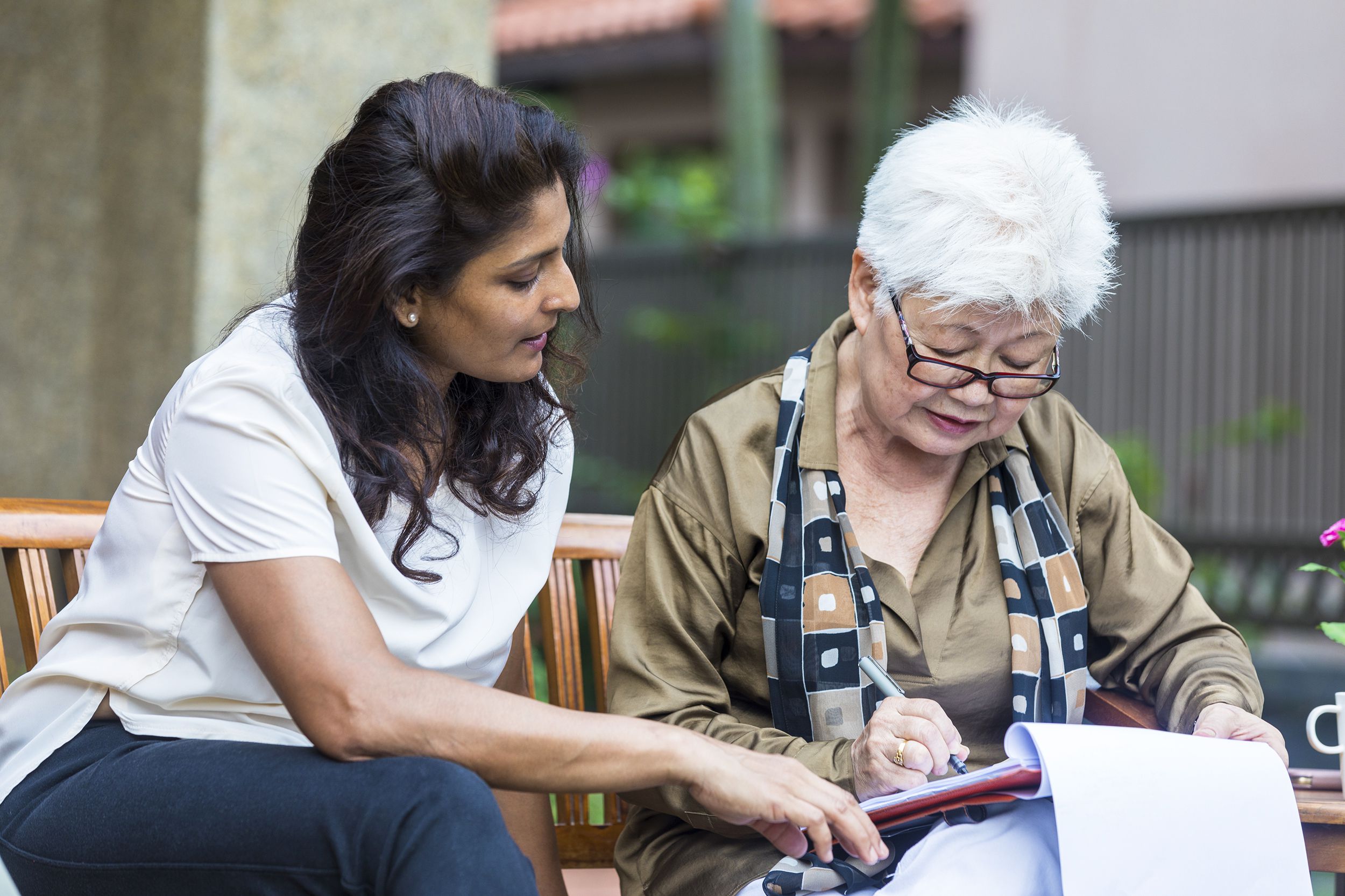 woman helping senior neighbor with paperwork