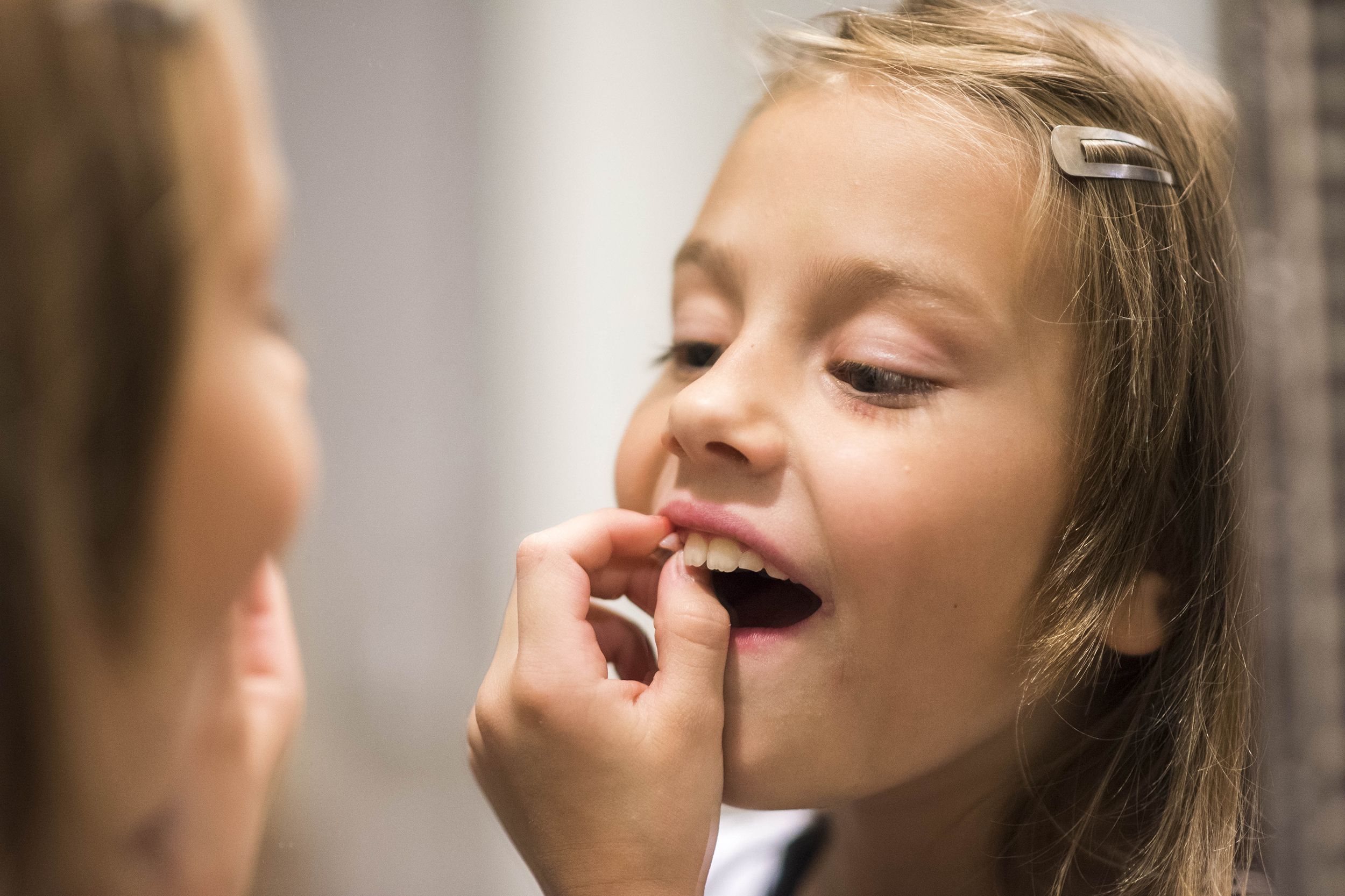 little girl pulling tooth out