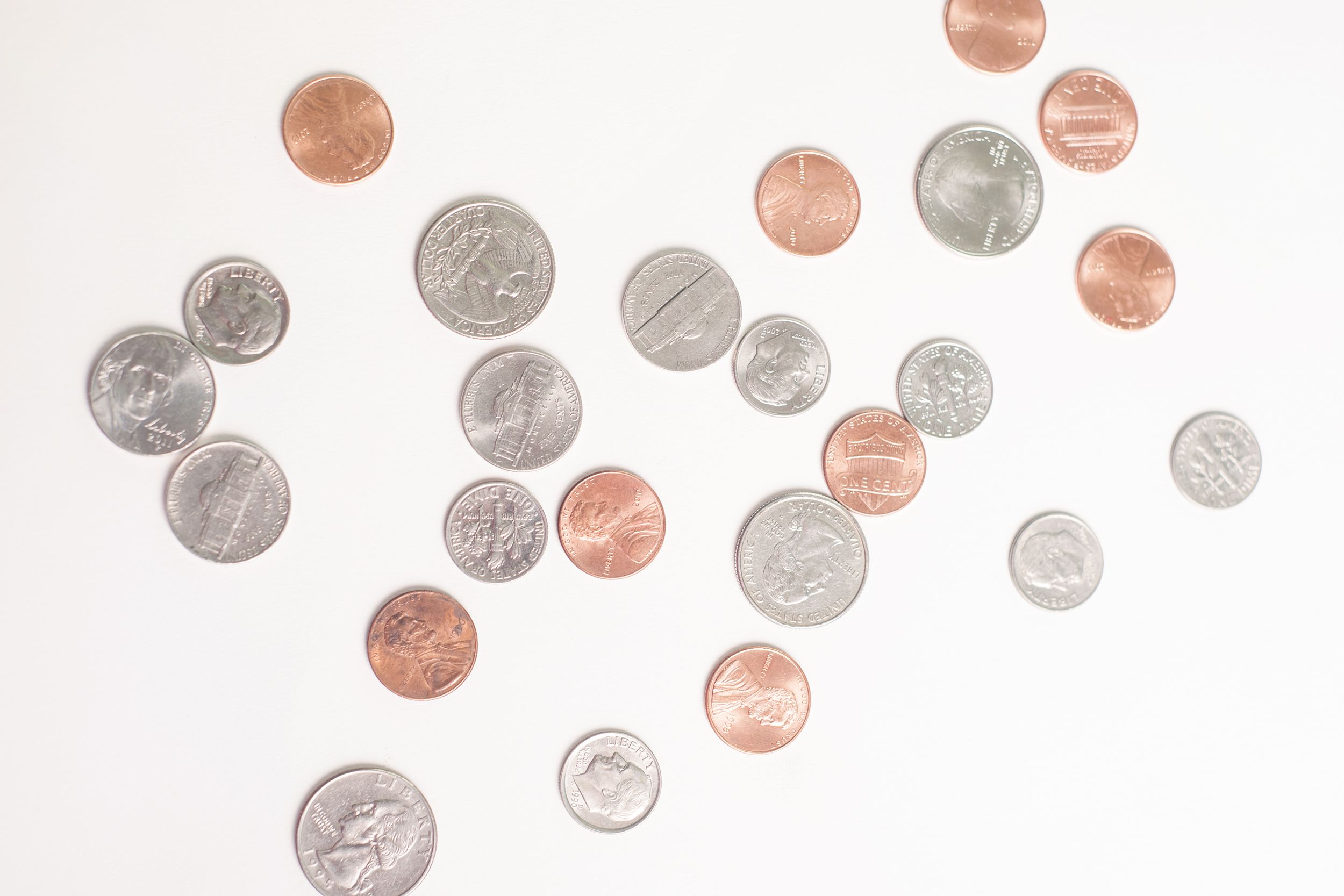 random US coins scattered on a white background