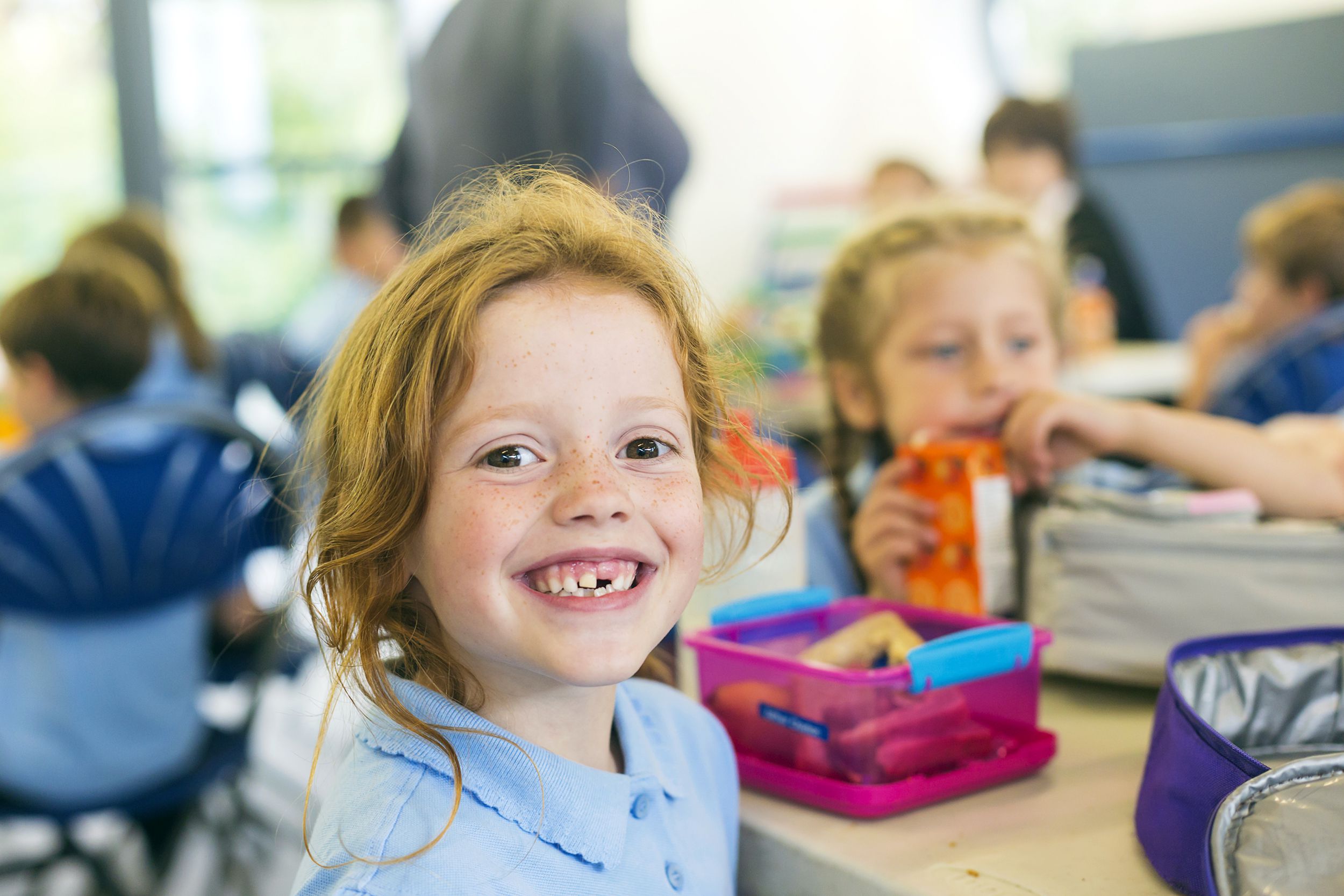 smiling girl missing a tooth at school lunch time