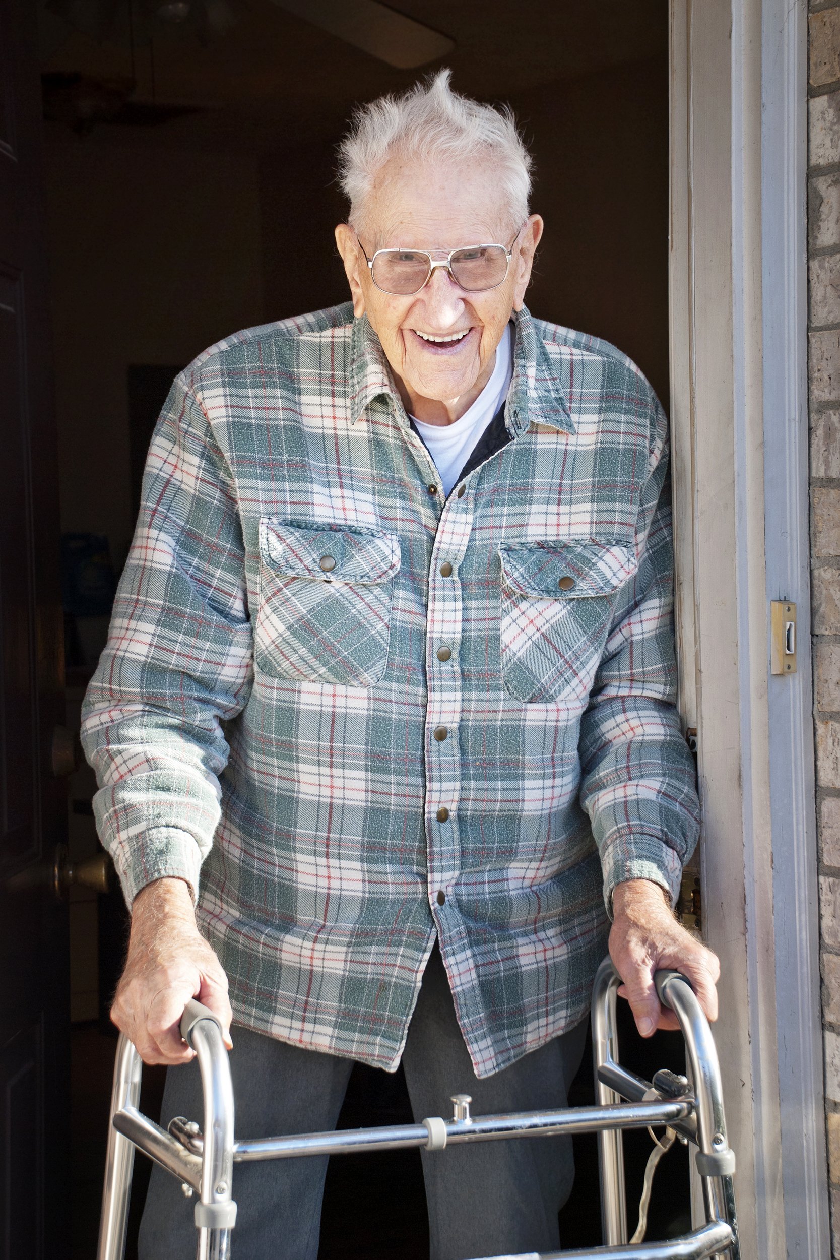 elderly man in his nineties with a walker standing in his apartment door