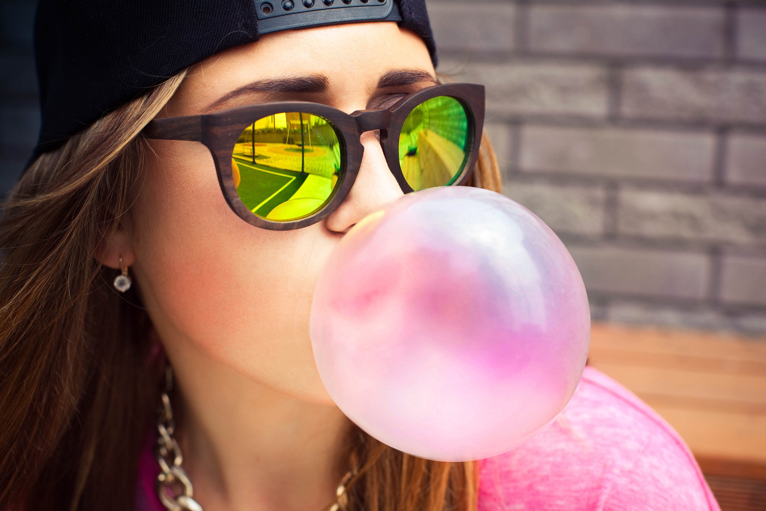 young woman blowing a bubble gum balloon