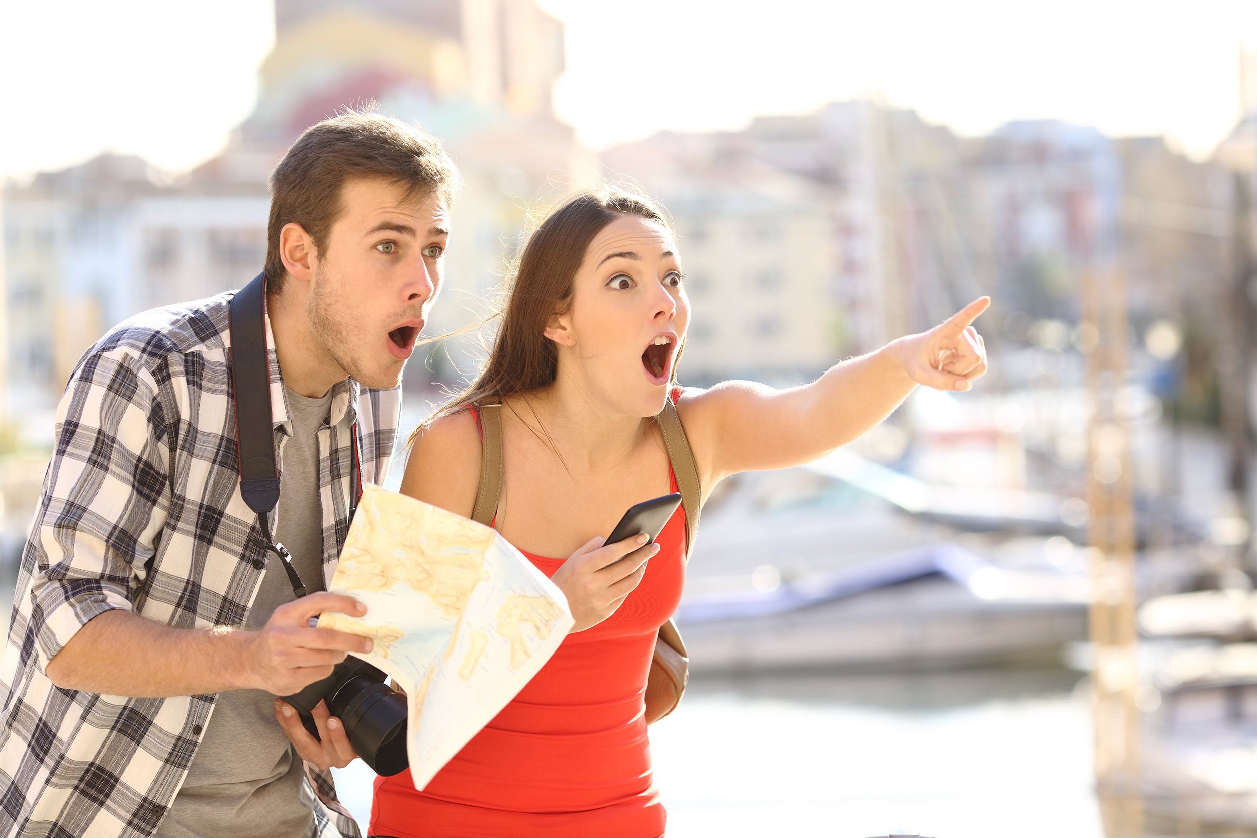 amazed couple of tourists finding location in a vacation travel with a port of a town in the background