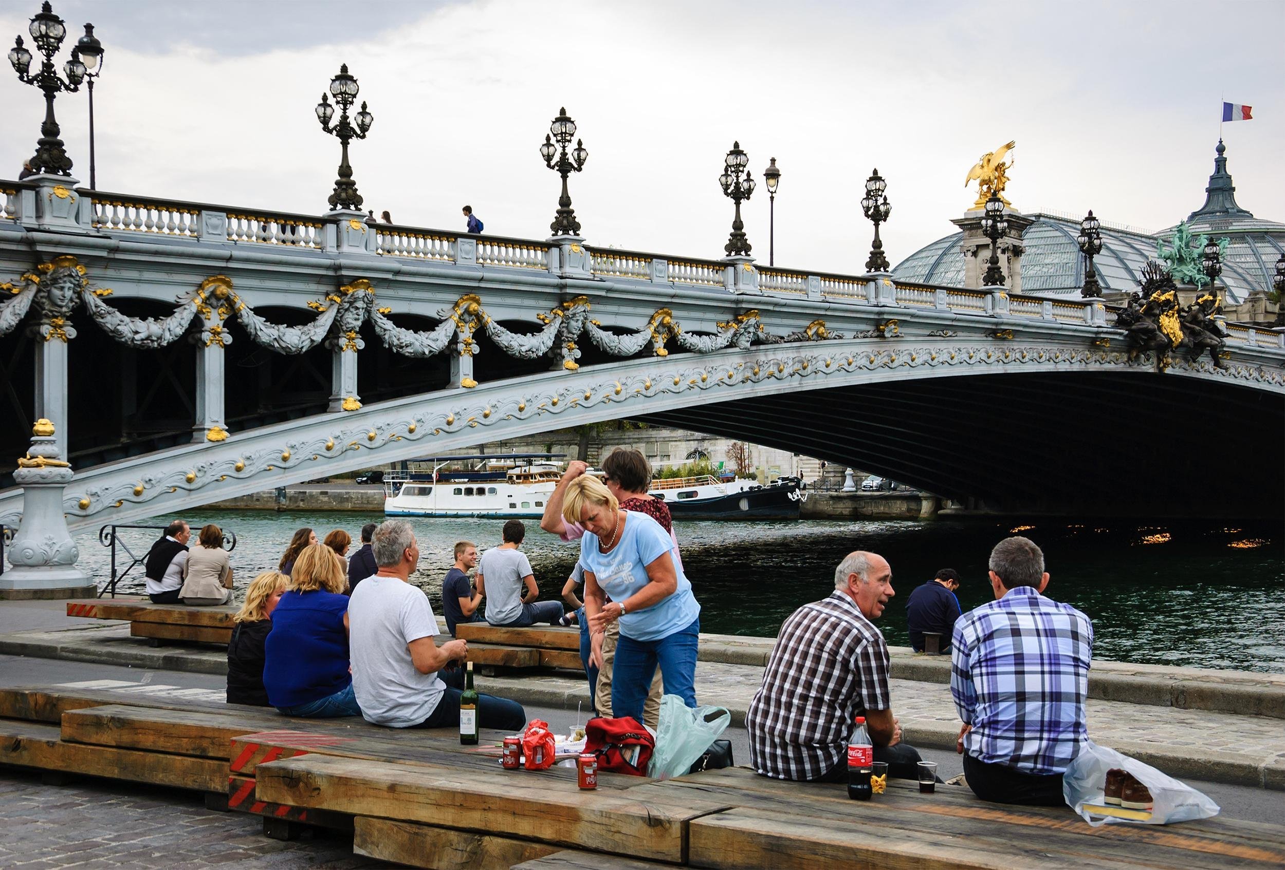 Parisians and tourists have picnic and relax near Pont Alexandre III
