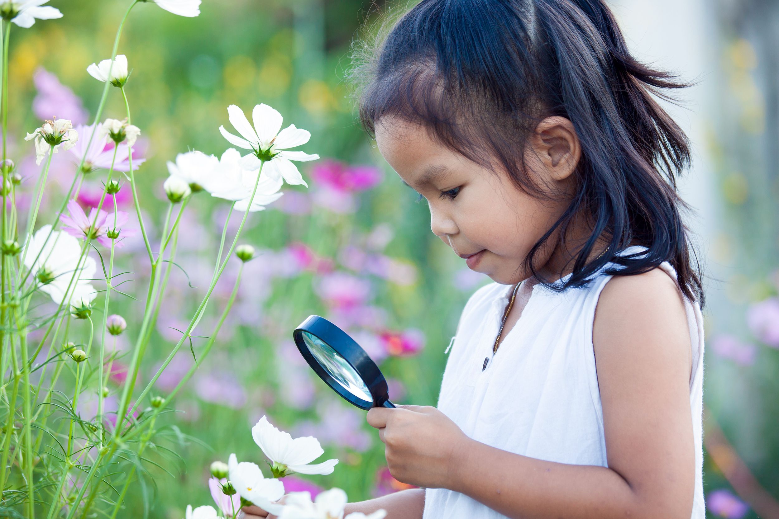 Young girl looking at flowers with a magnifying glass