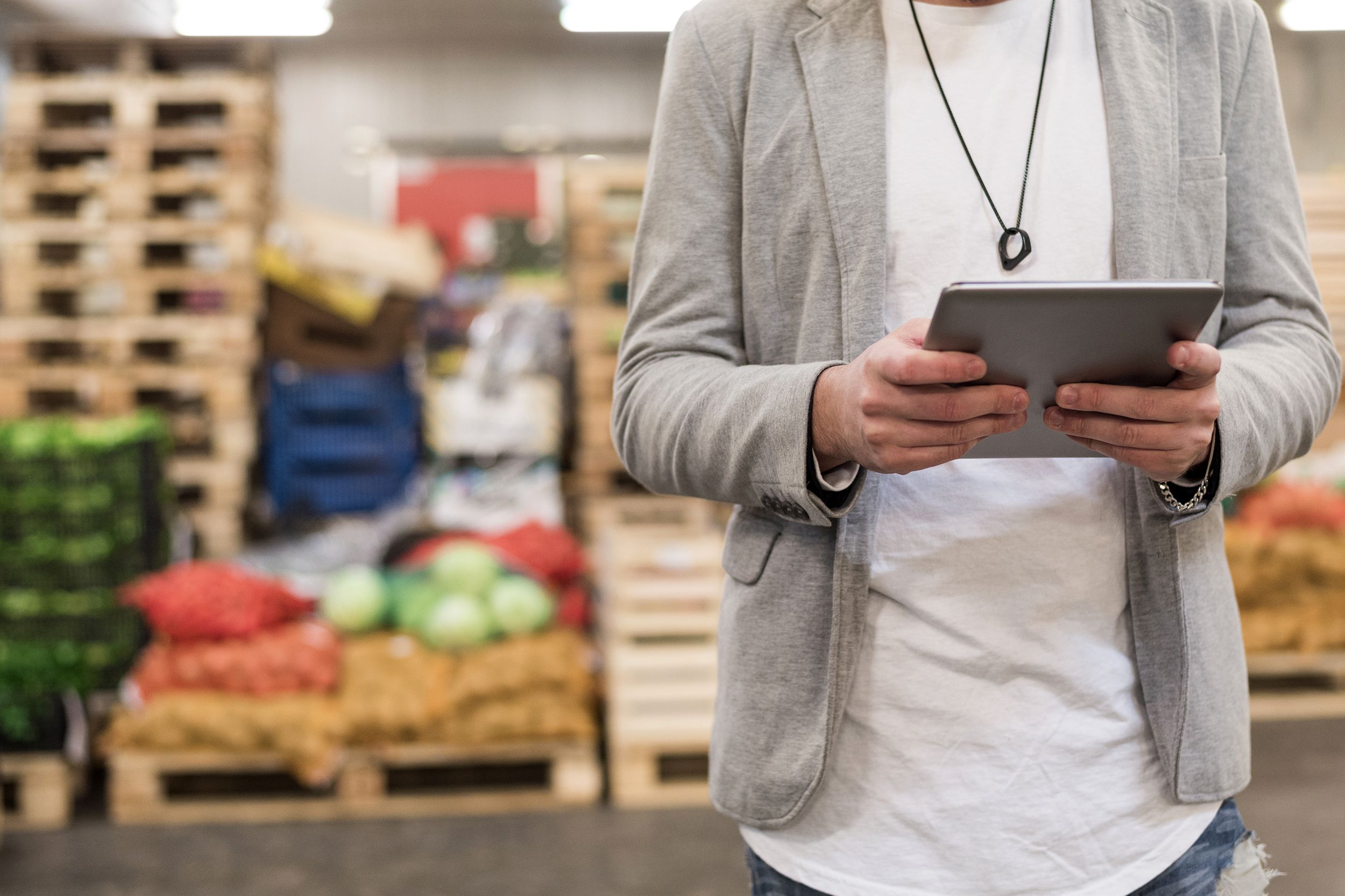 Closeup of man in a grocery store warehouse holding a tablet